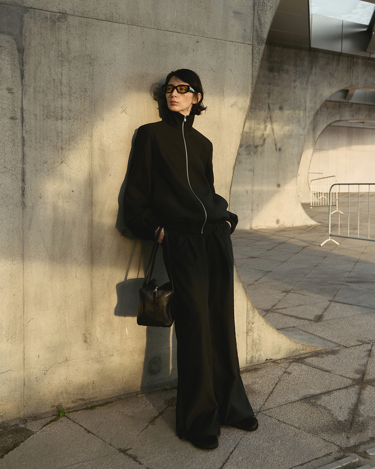 Urban catalogue before retouching — black oversized jacket, concrete background