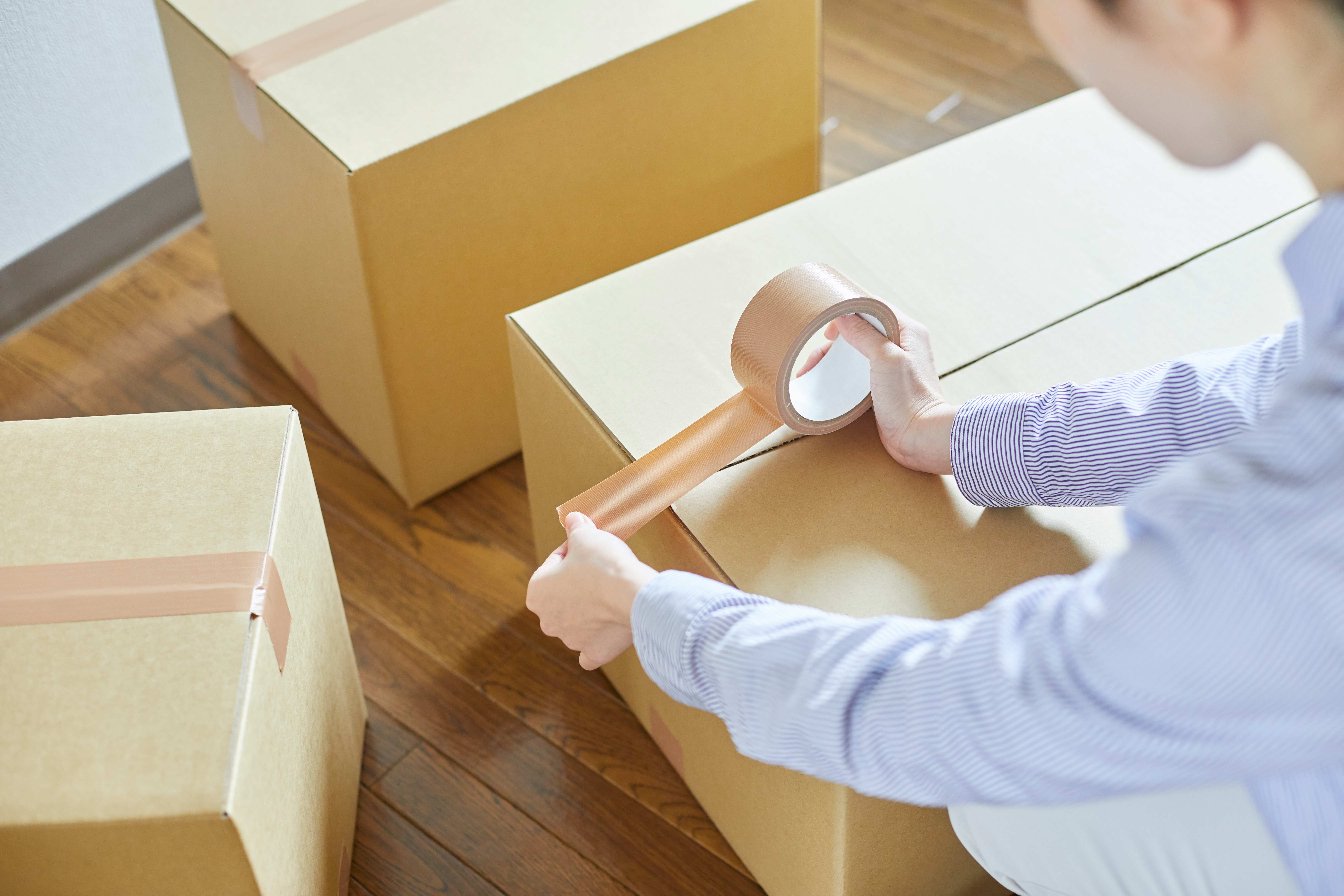 Frau verpackt Umzugskartons mit Klebeband