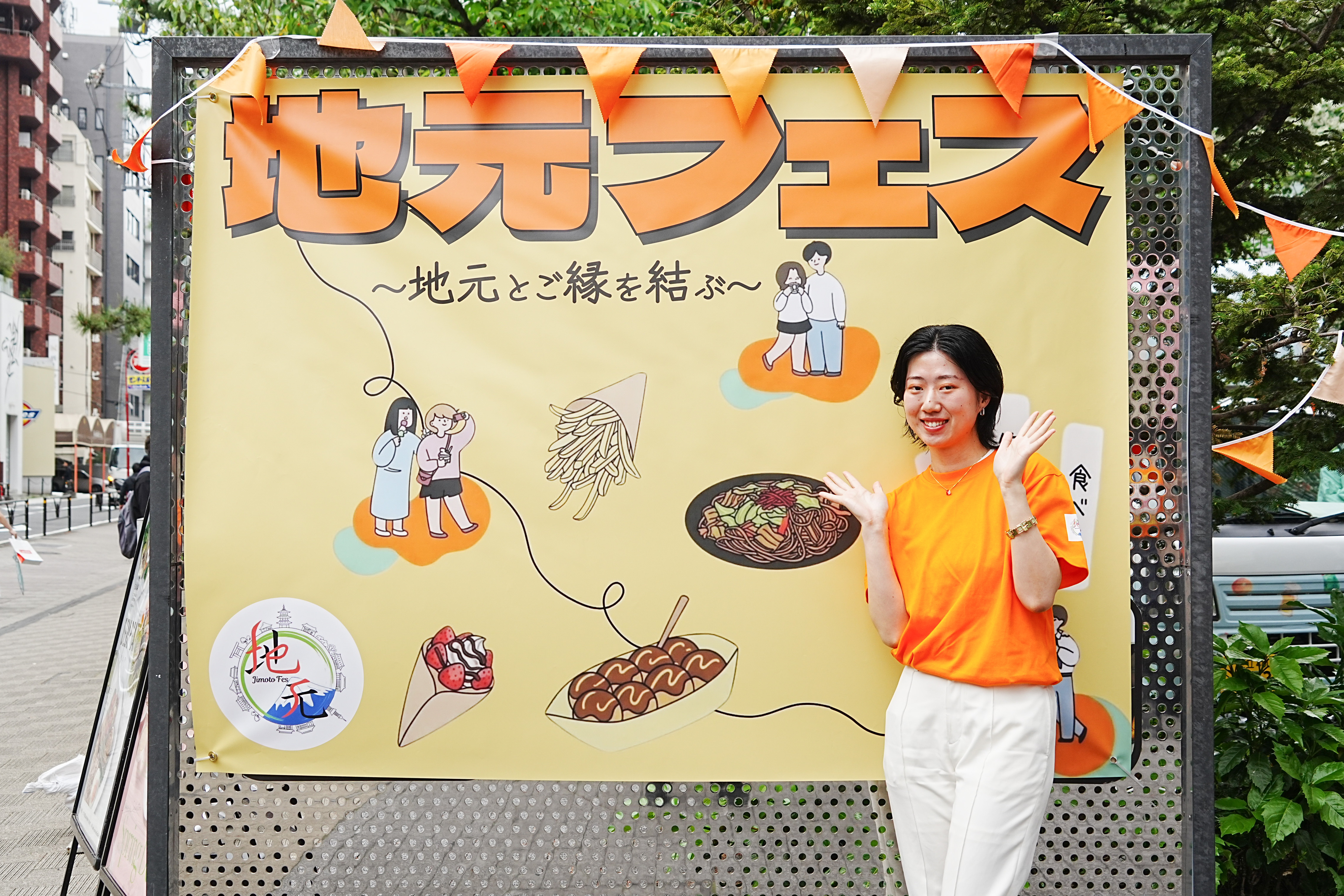 地元フェス看板の前のスタッフ