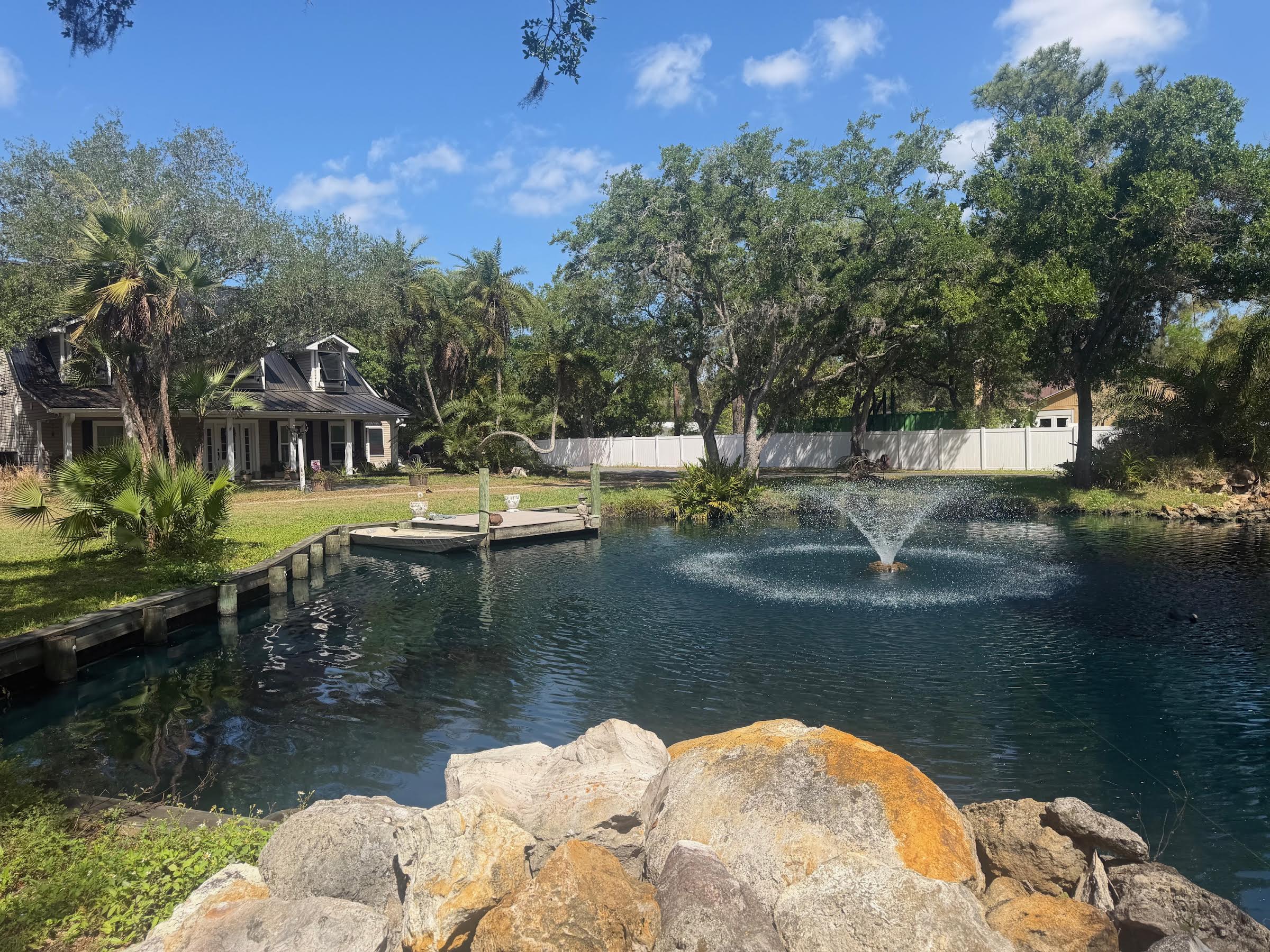 Wood seawall along pond with fountain and residential property