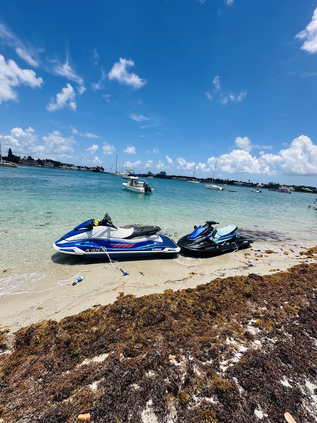 Two jet skis beached on sandy shore with turquoise water at Peanut Island