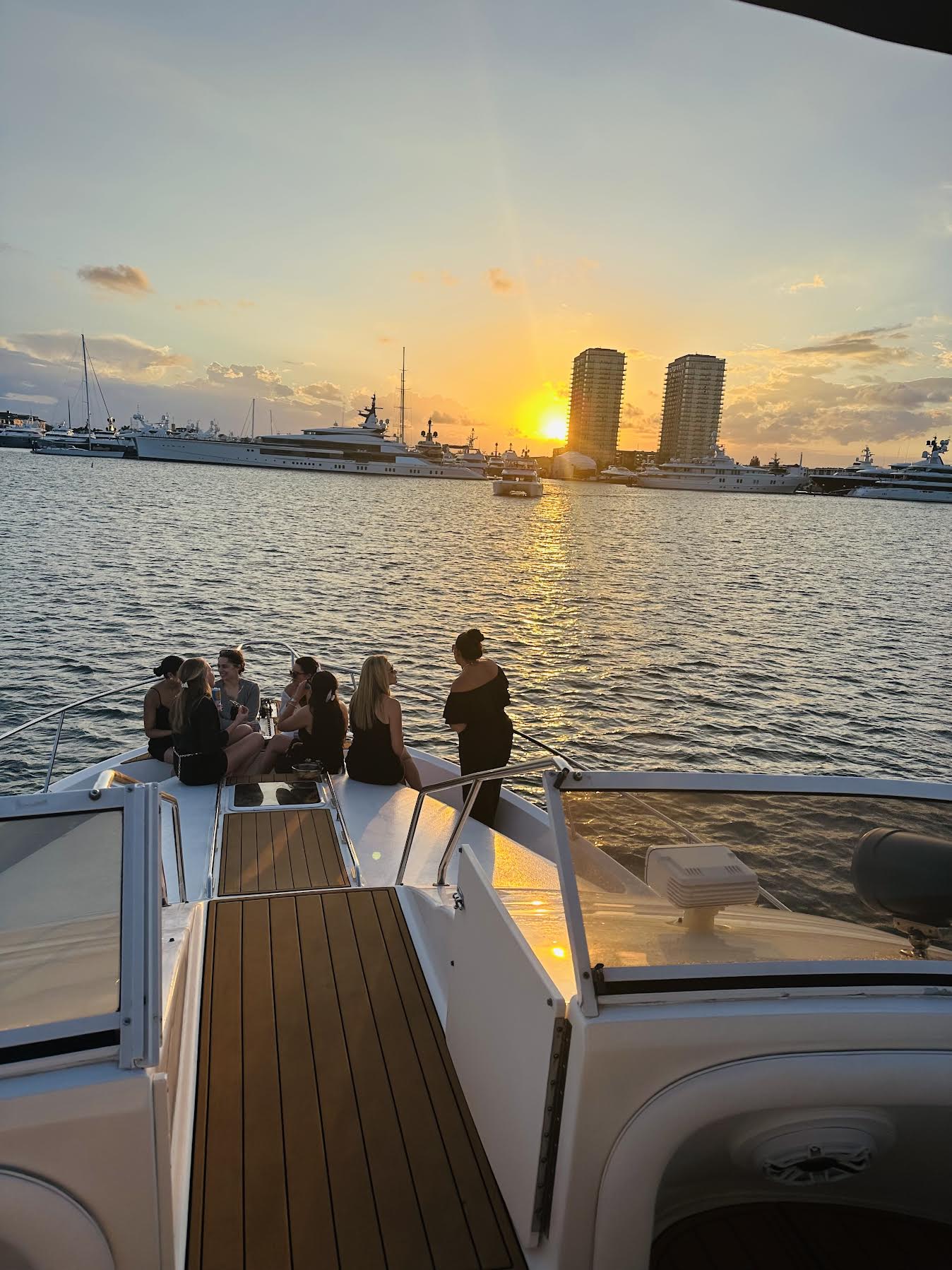 Guests watching sunset from yacht bow with marina and towers