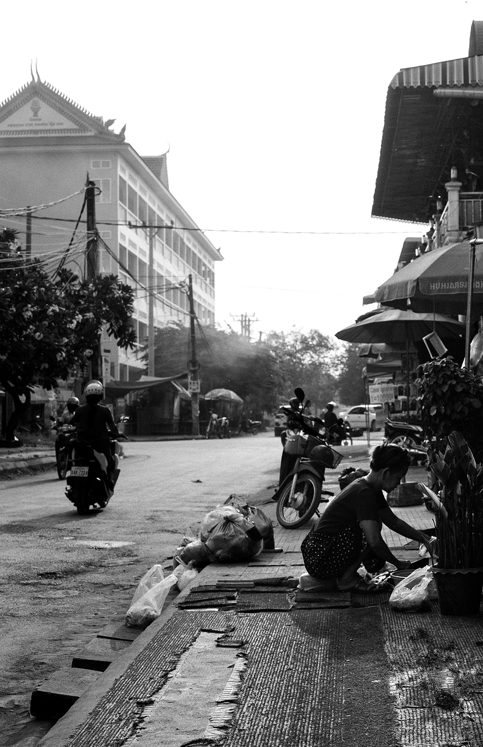 Urban street scene with motorcycle passing ornate temple with distinctive spires and power lines