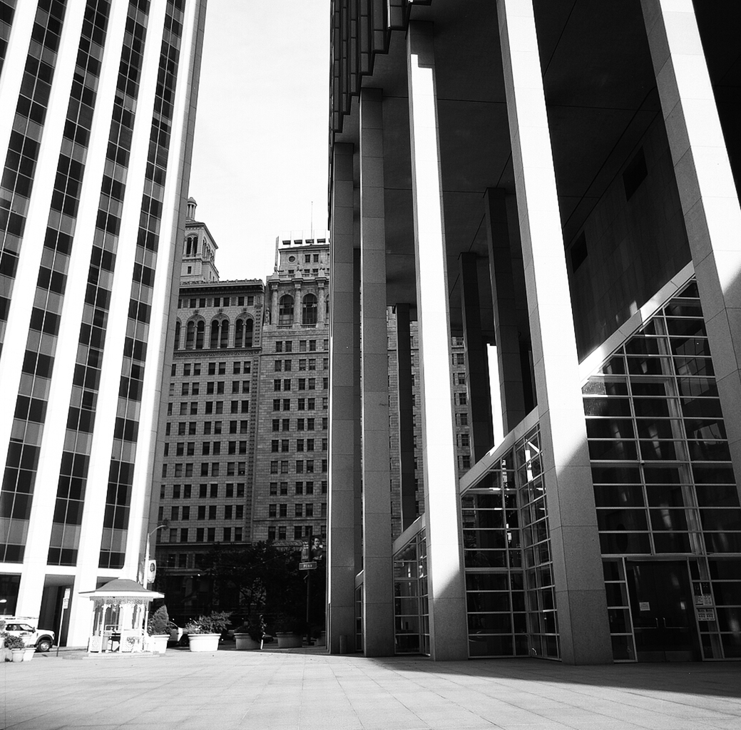 Downtown financial district canyon with tall glass buildings, ornate historical building framed between modern towers