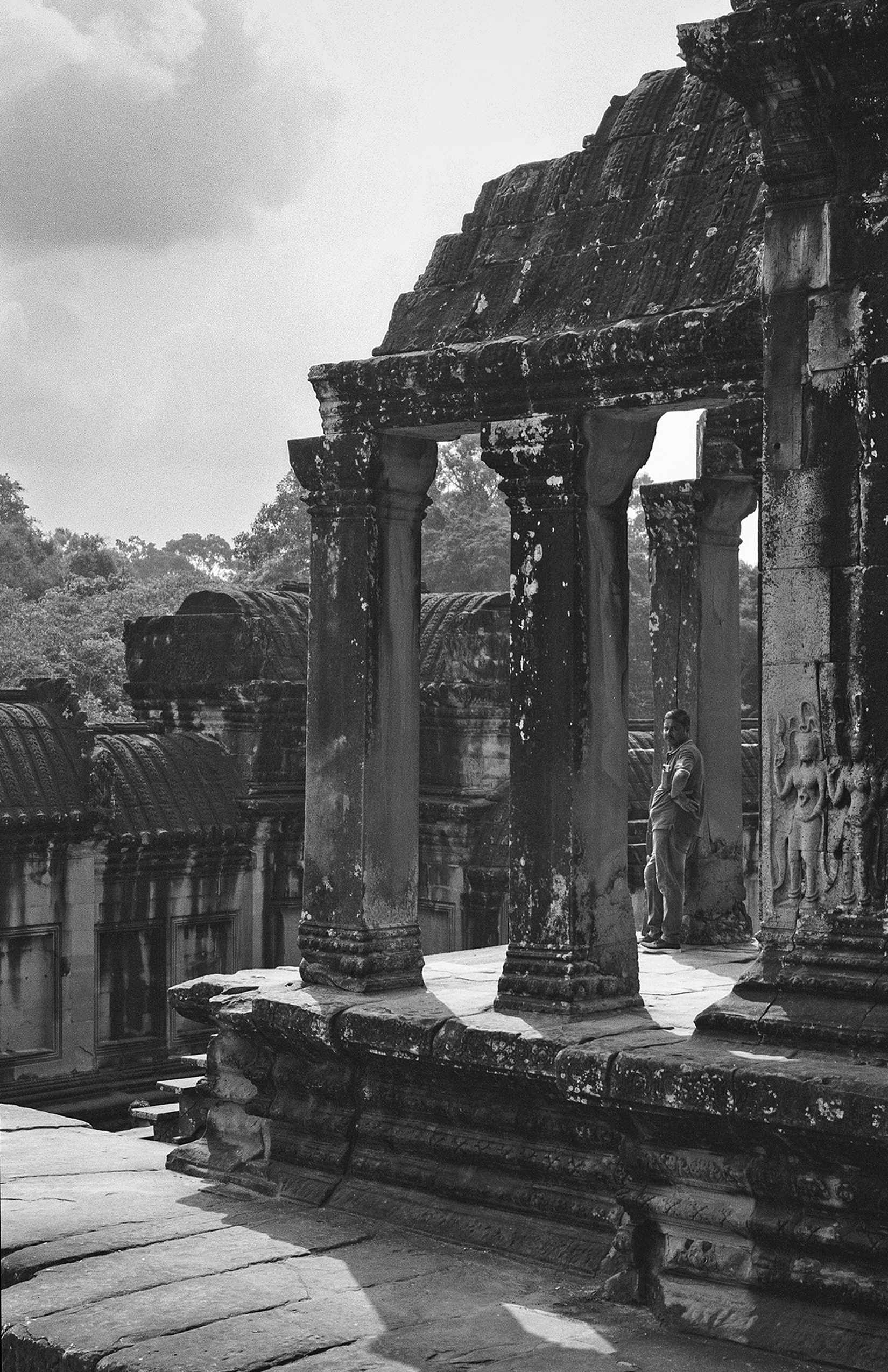 Angkor Wat temple gateway with colonnade and relief carvings framing distant landscape