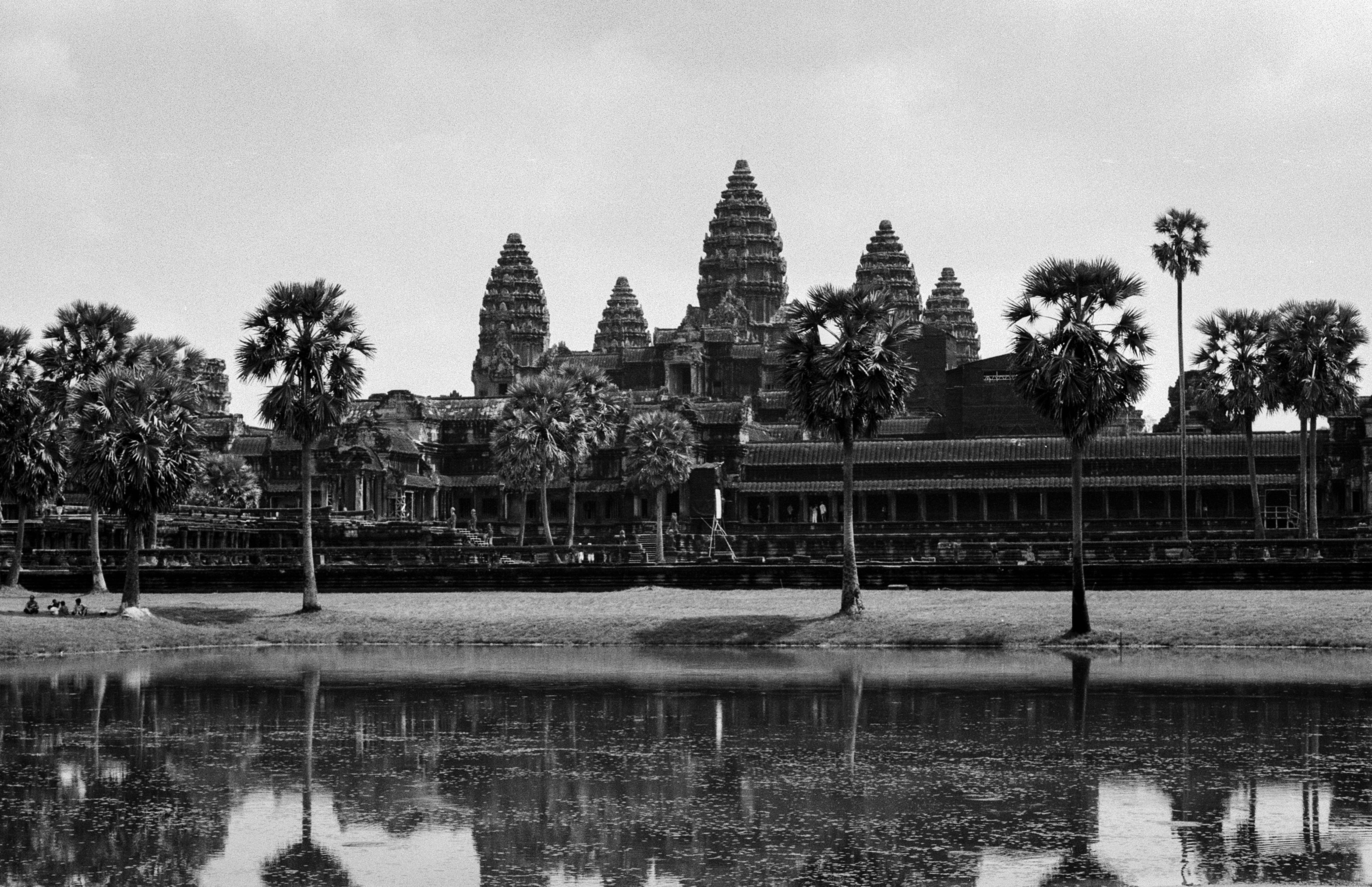 Angkor Wat temple with distinctive spires and palm trees along waterfront view