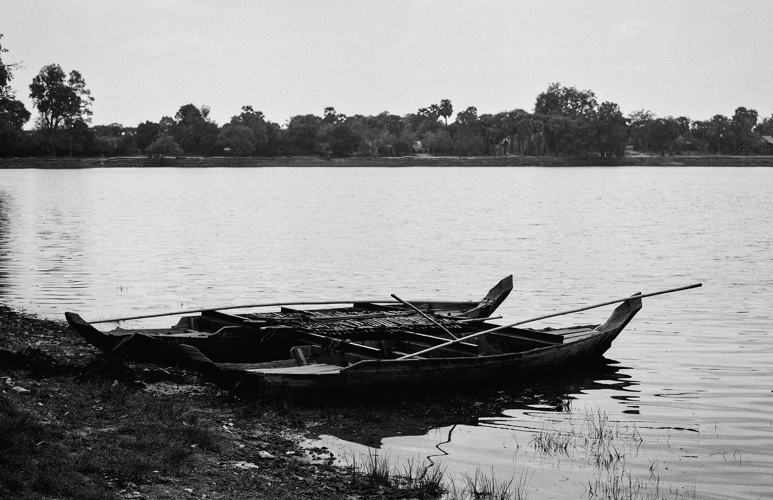 Traditional wooden boats moored at riverbank with forest and water landscape