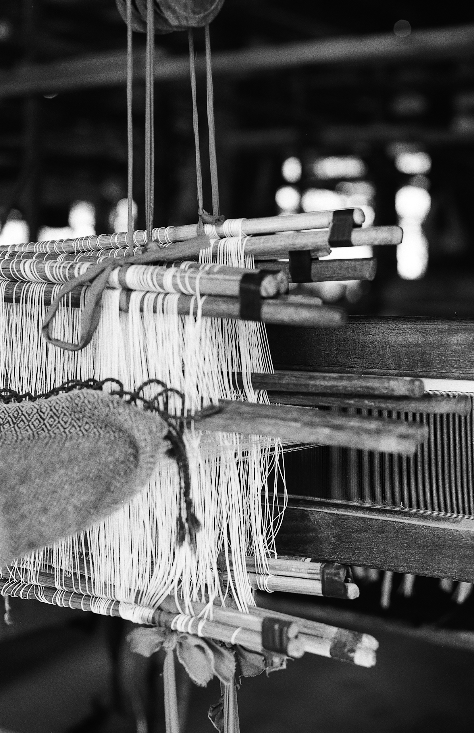 Detailed close-up of wooden weaving loom with white thread and mechanical parts
