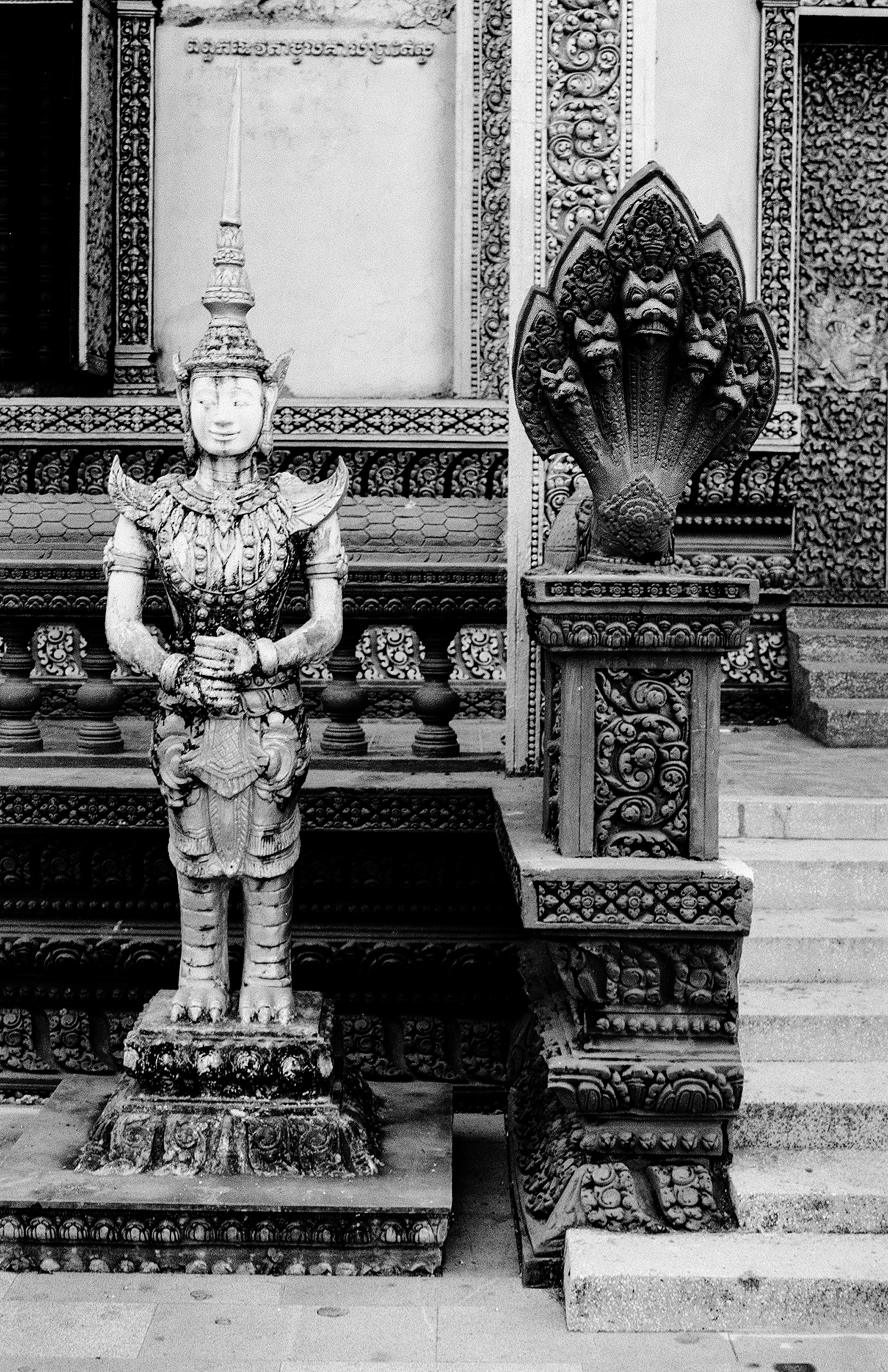 Stone guardian figure in formal ceremonial dress at ornate temple courtyard