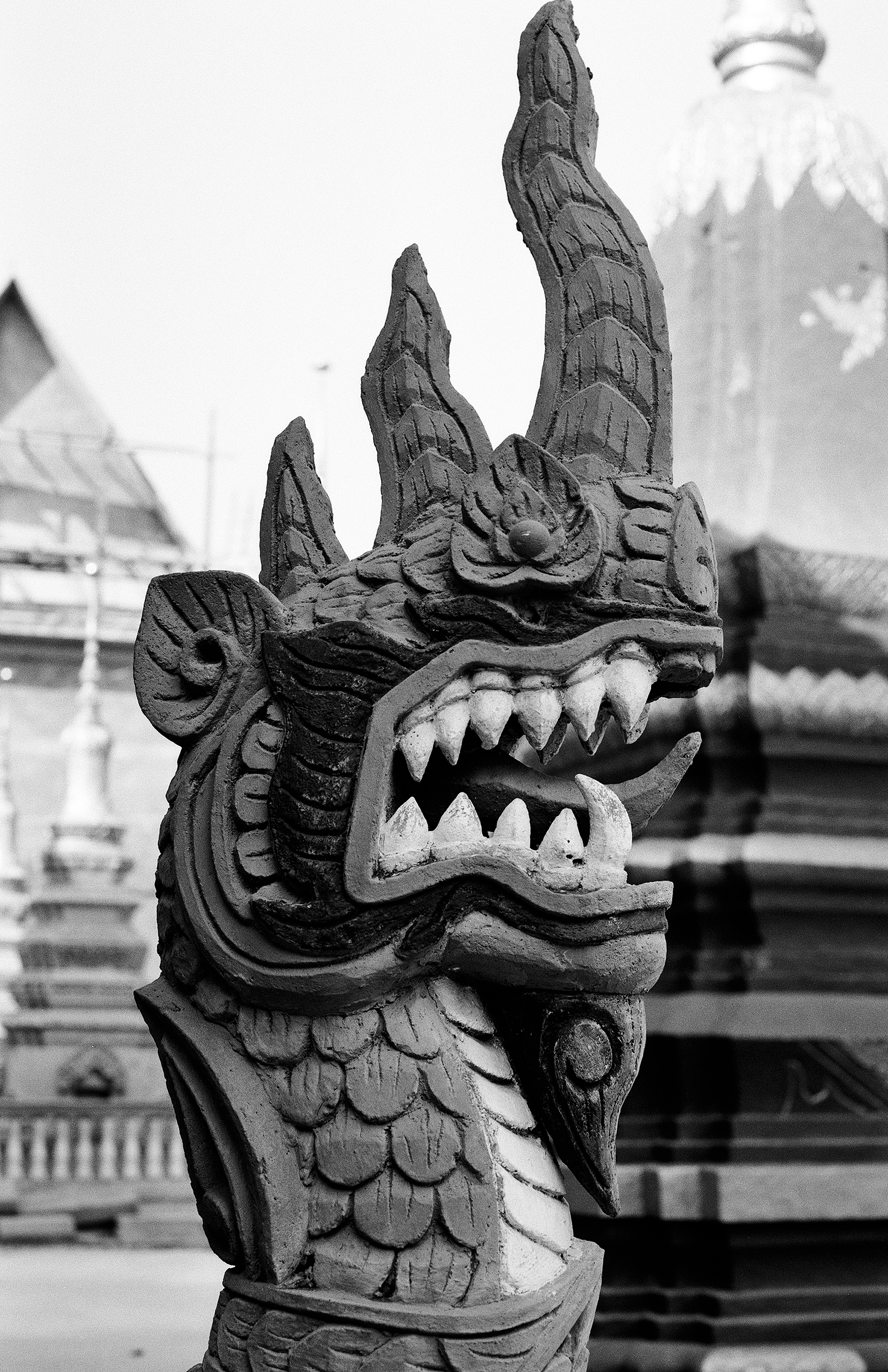 Intricately carved wooden dragon head sculpture with fangs at temple entrance