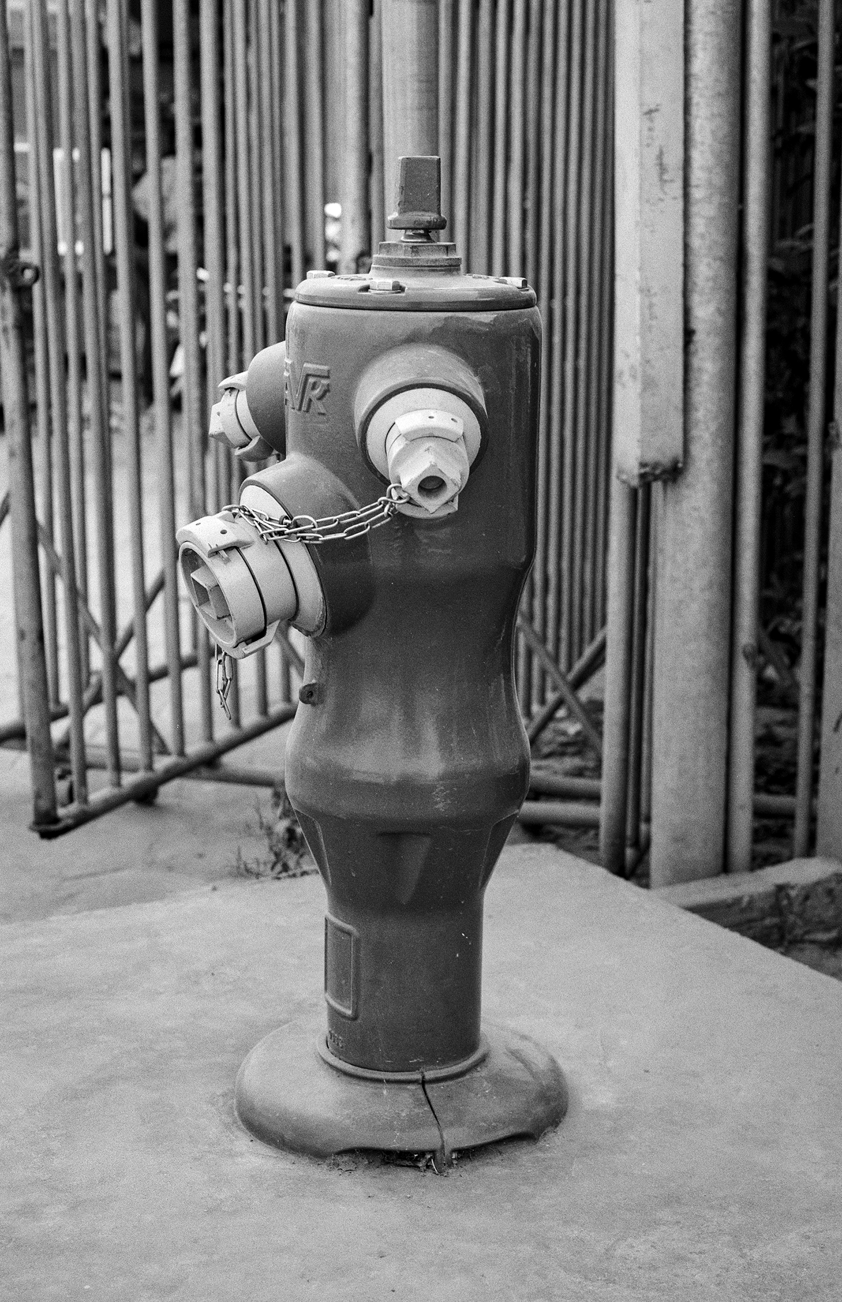 Fire hydrant with chain and metal bands against corrugated metal fence wall