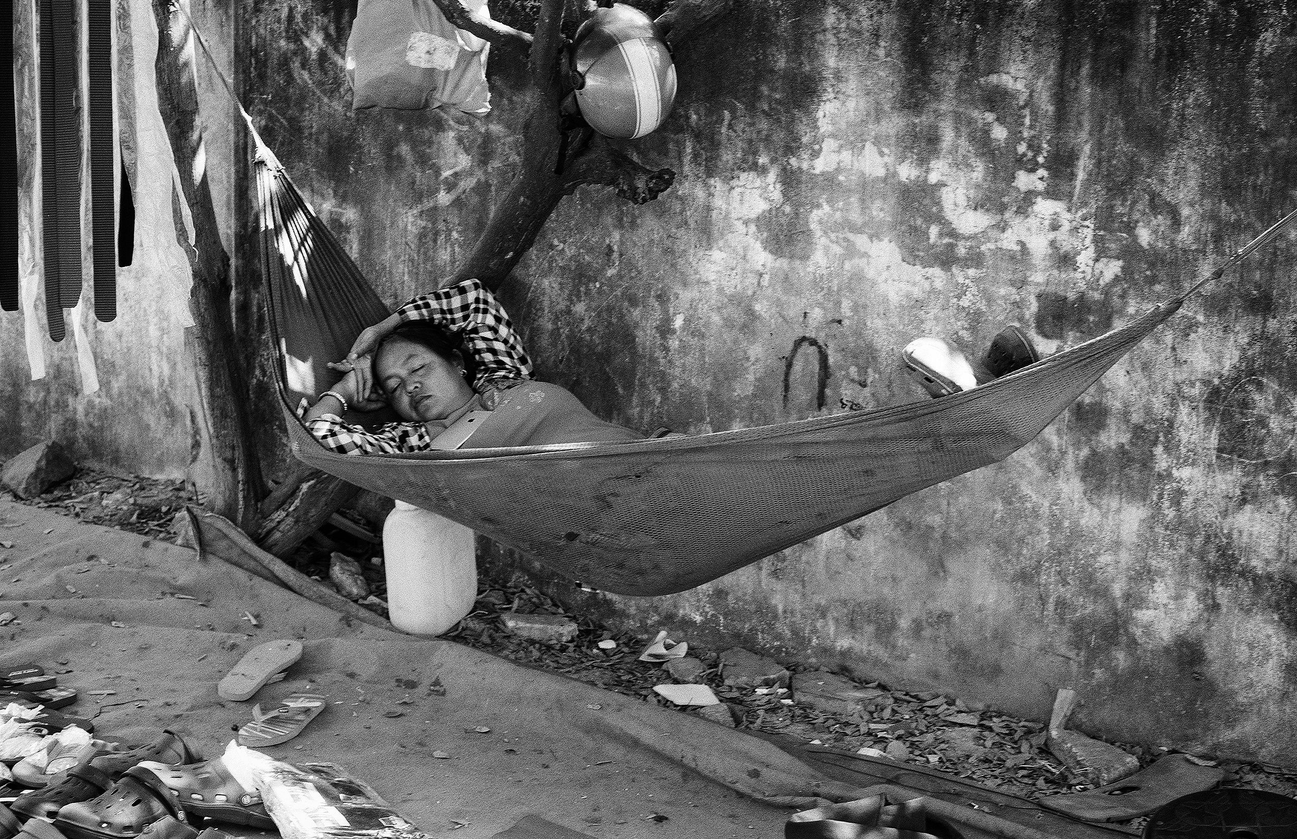 Man resting in hammock wearing checkered shirt with domestic items nearby