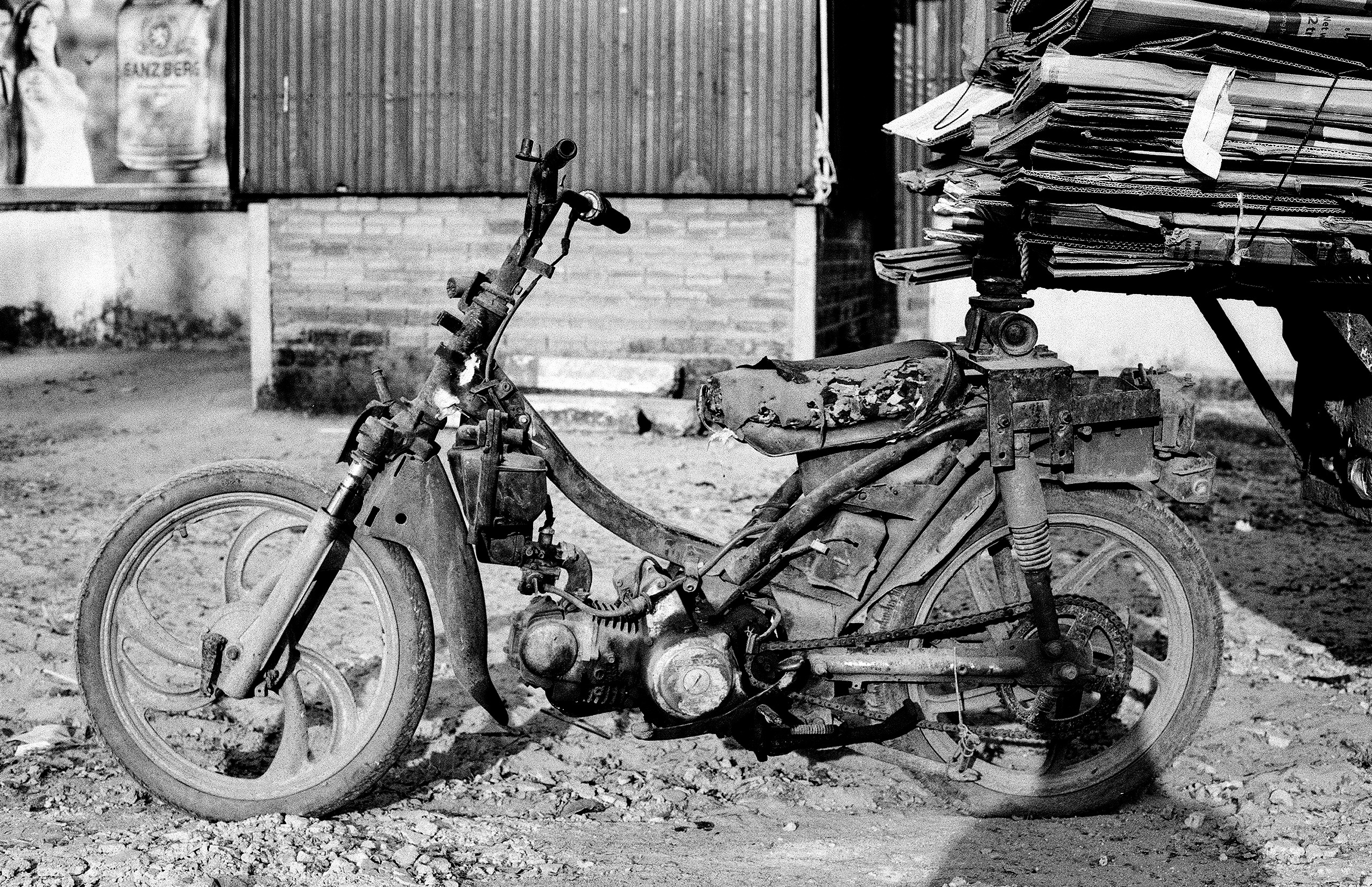 Damaged and weathered motorcycle in disrepair with stacked metal sheets