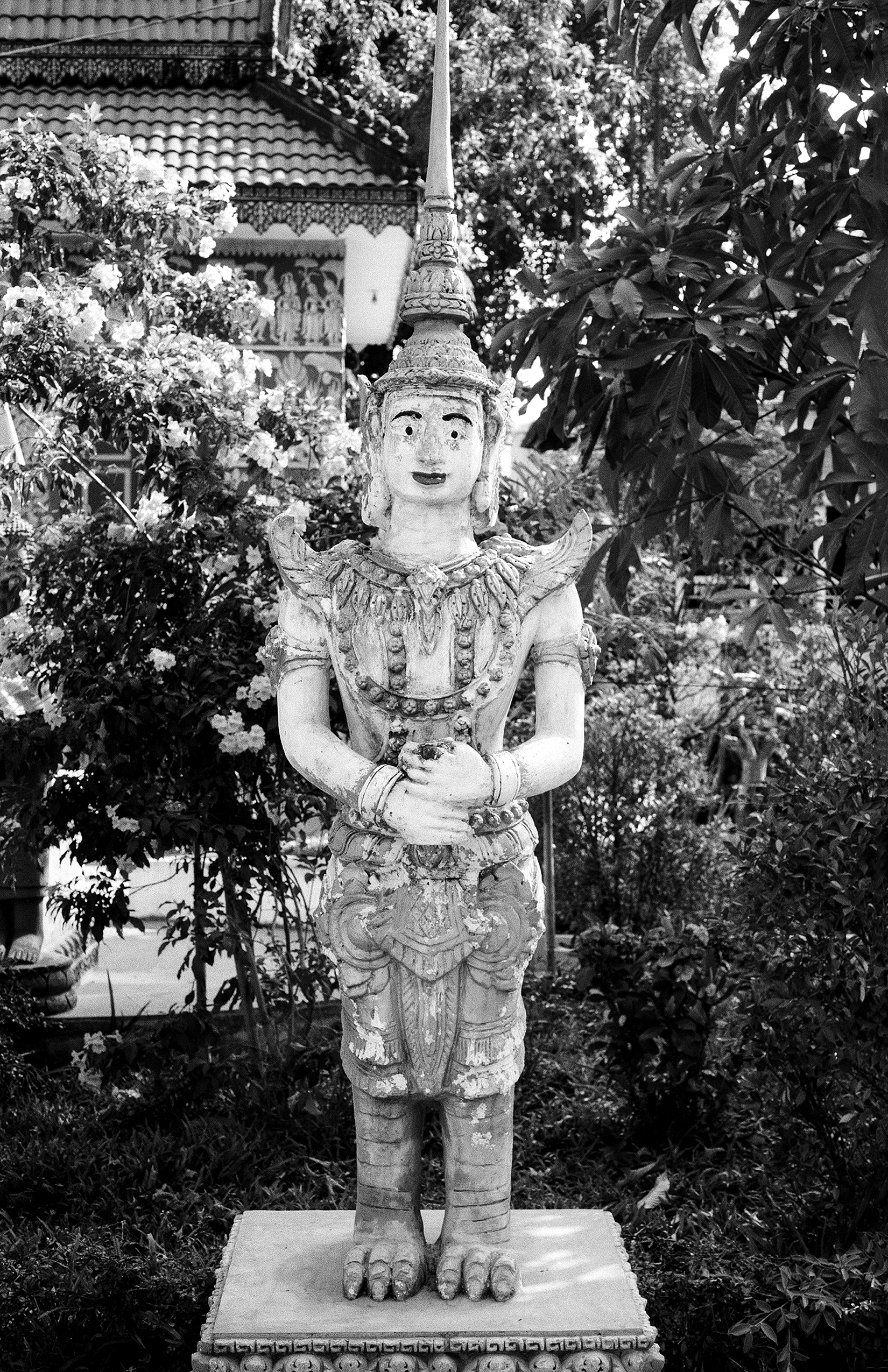 Elaborately carved seated deity statue with tall pointed headdress in temple