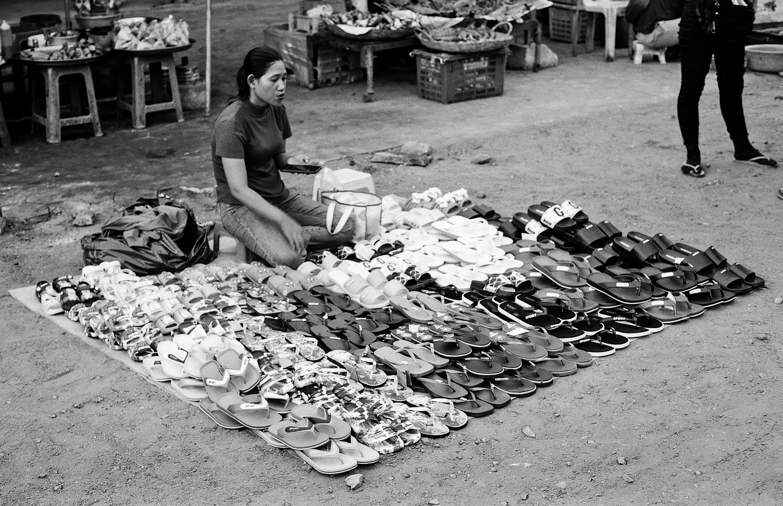 Woman kneeling surrounded by extensive display of colorful shoes and sandals