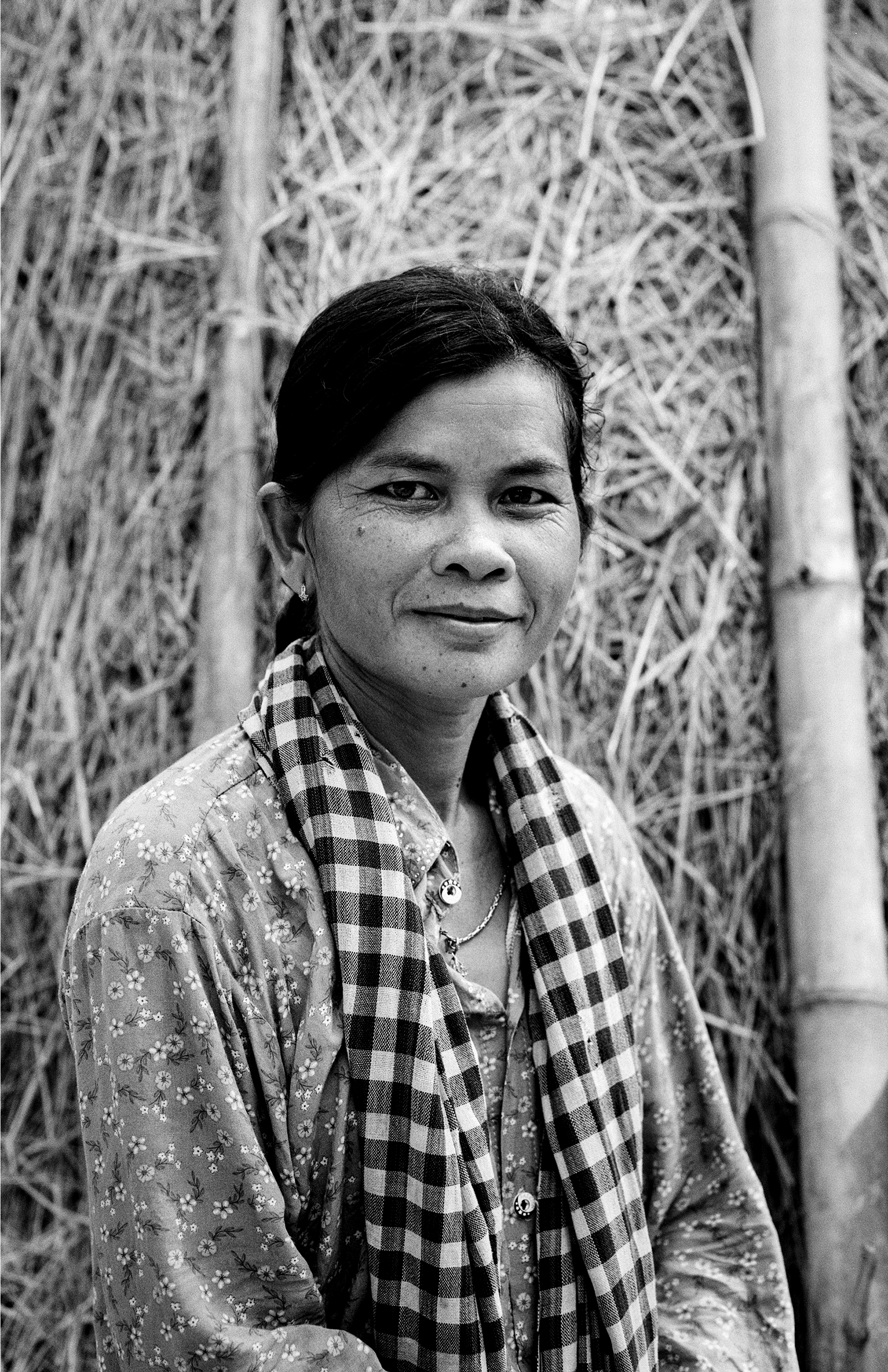 Woman in traditional patterned clothing standing in front of thatched bamboo structure