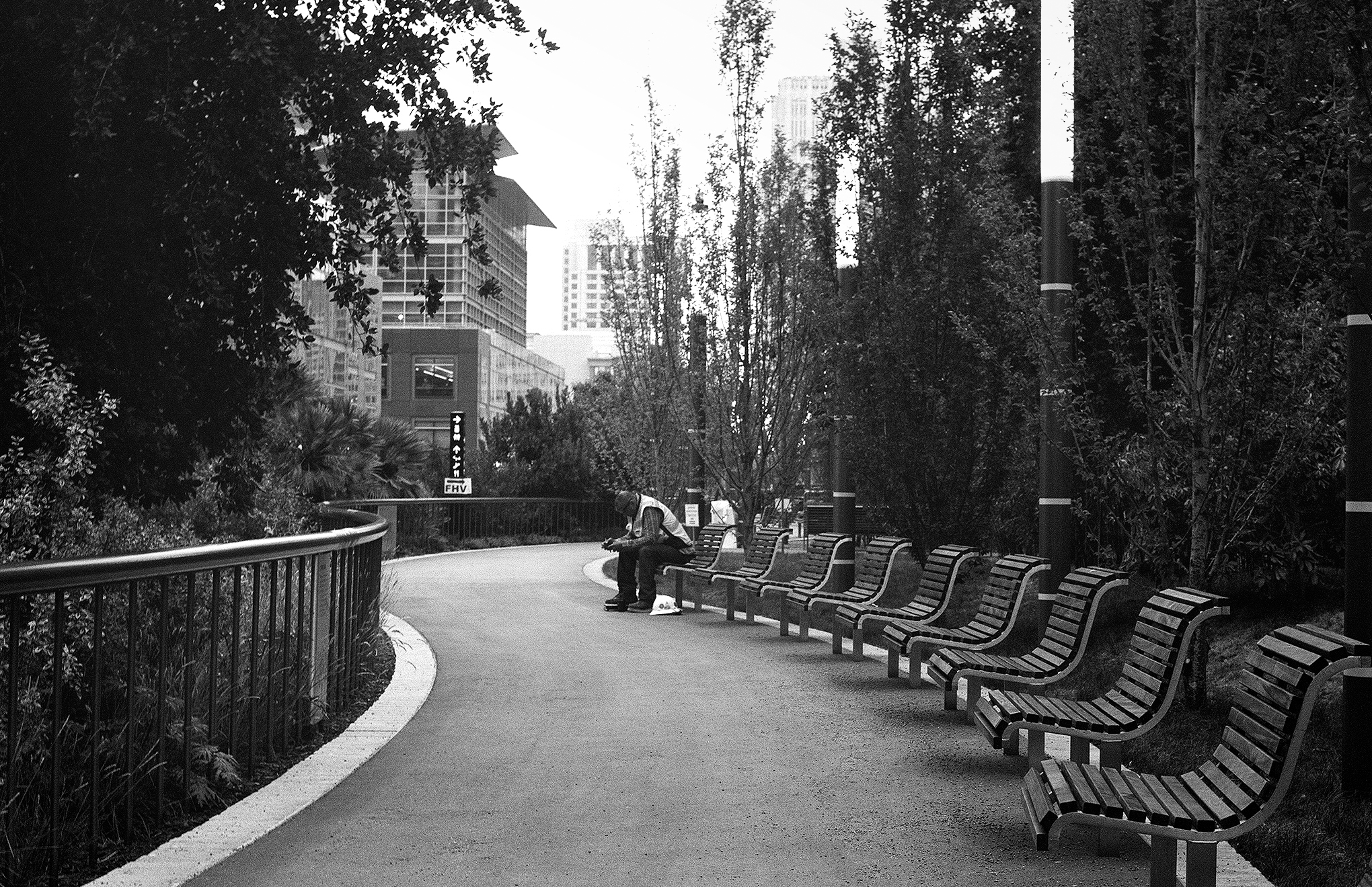 Market Street scene with person crouched near tree and pedestrian walking on brick plaza