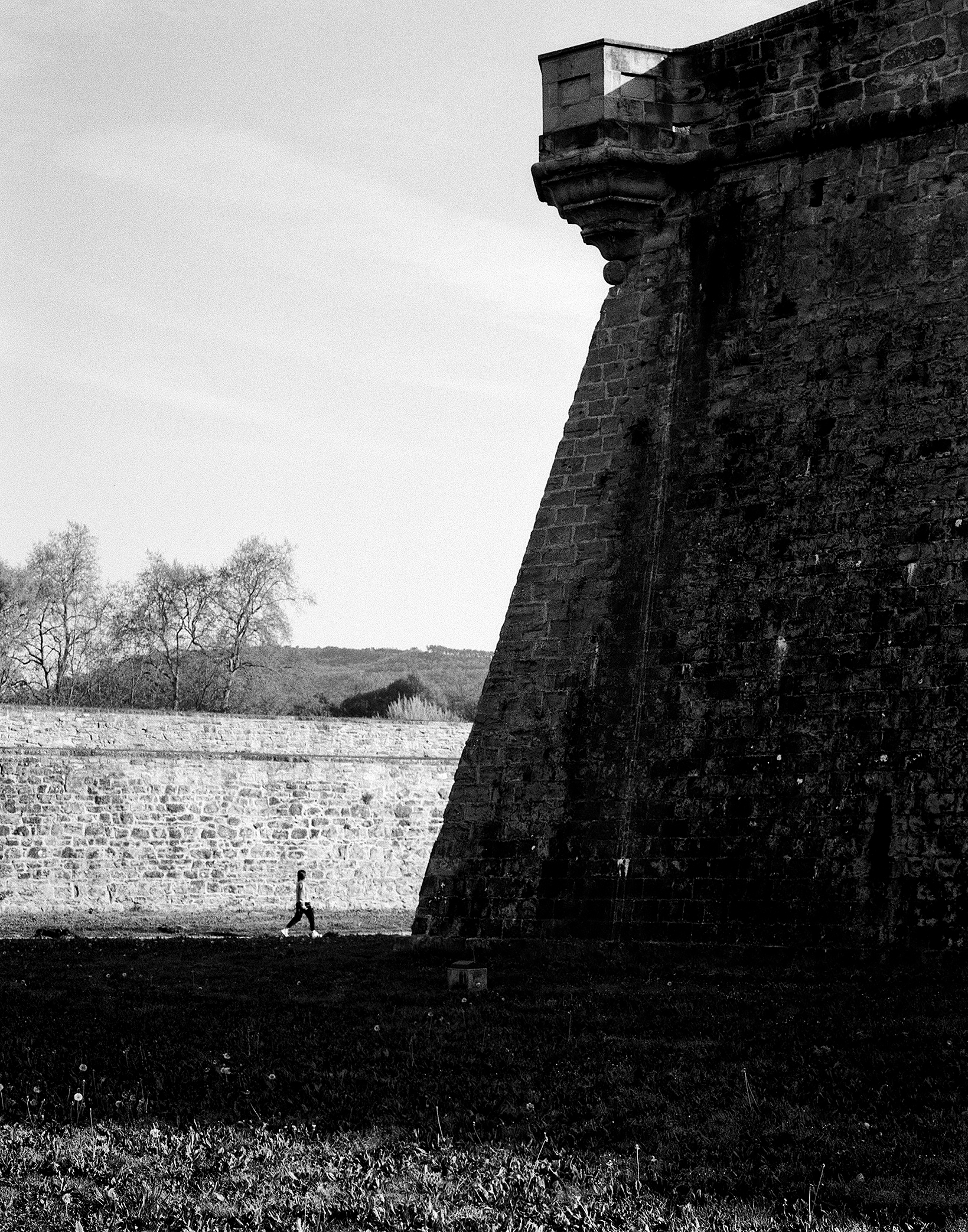 Massive stone fortress corner tower with steep angled wall and white stone face
