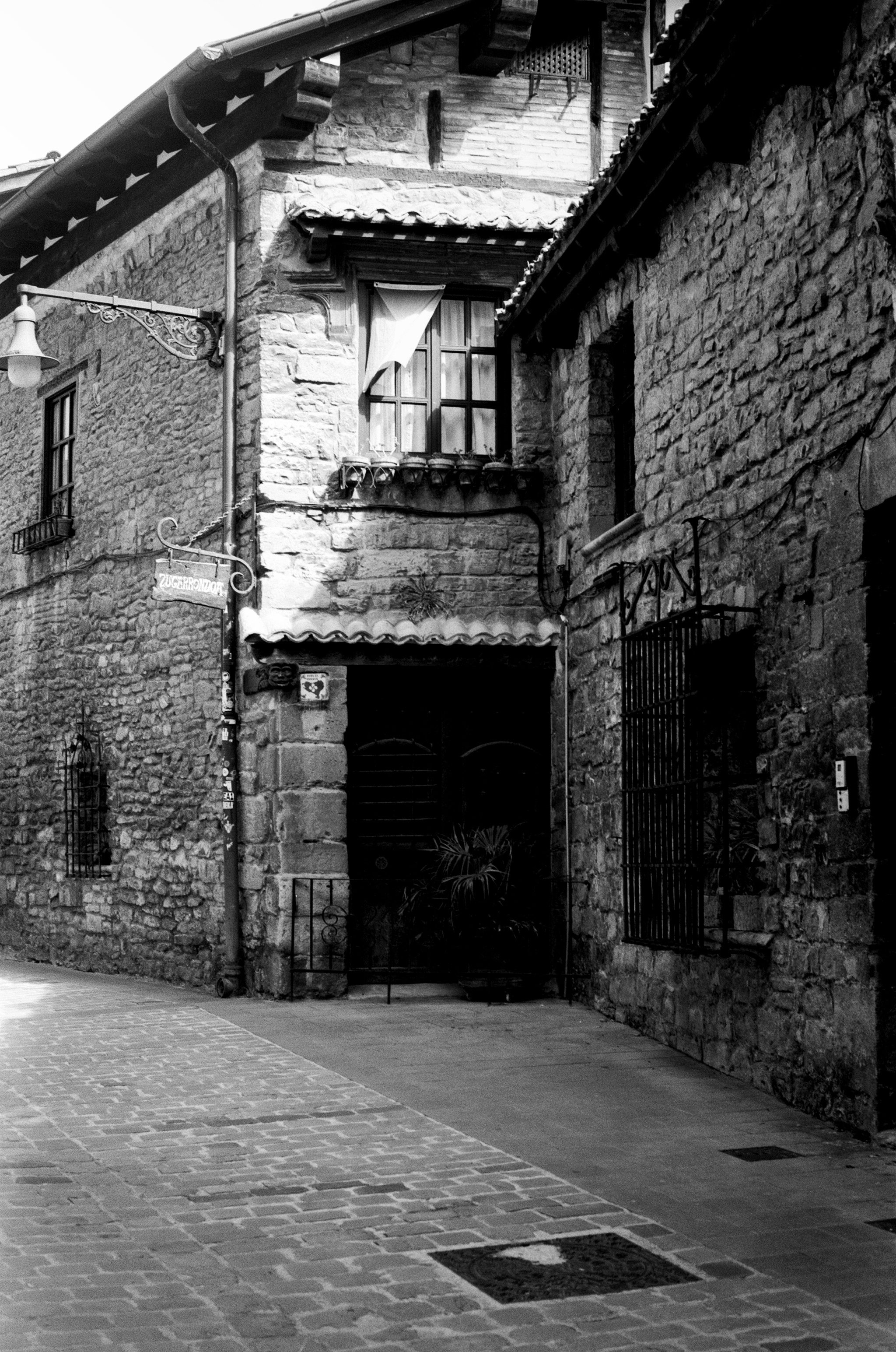 Historic stone building with ornate window grille and iron balcony details in narrow urban street
