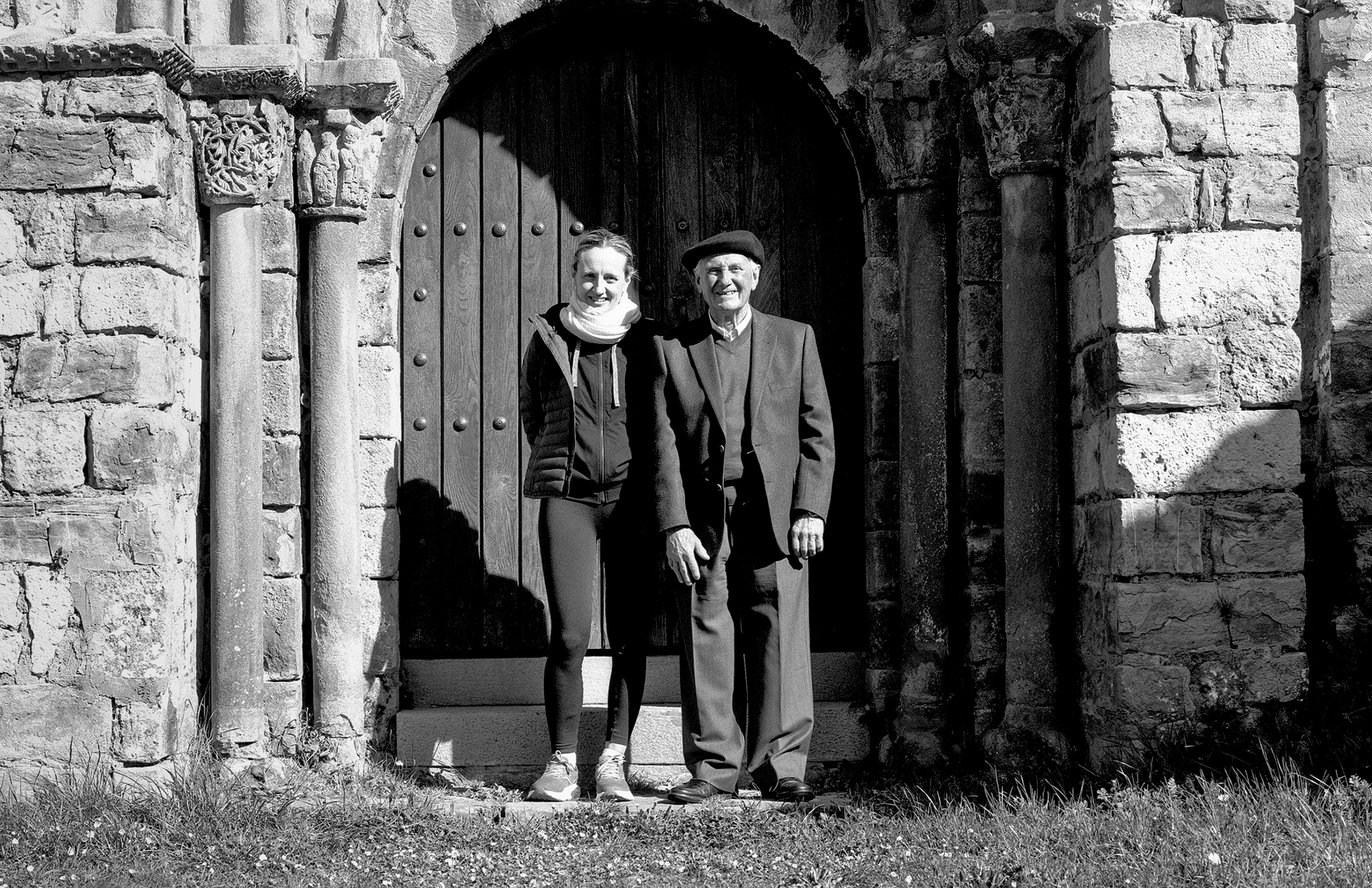 Two figures standing together in stone archway gateway with classical architectural details