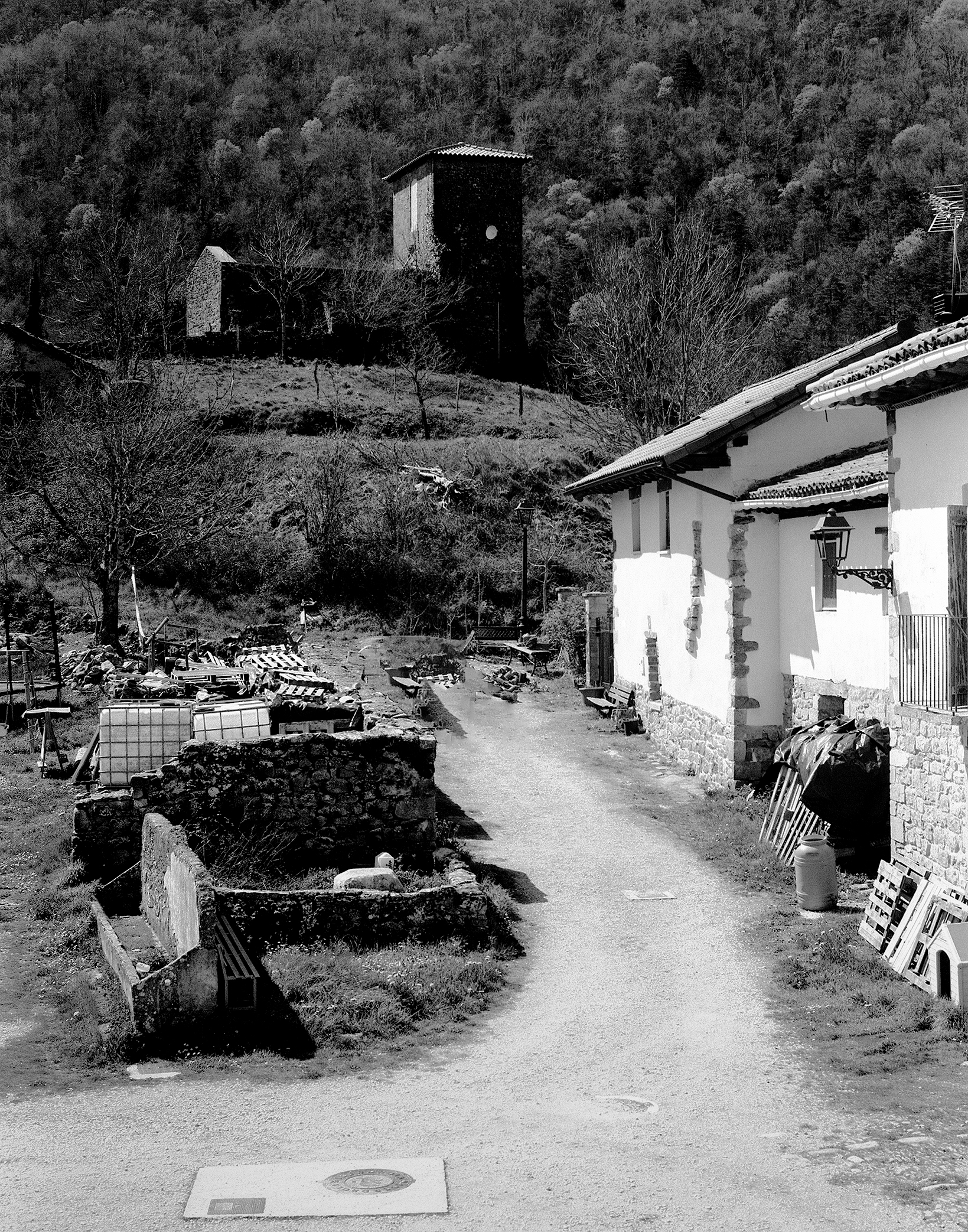 Rural village with white building and watchtower rising from forested hillside landscape