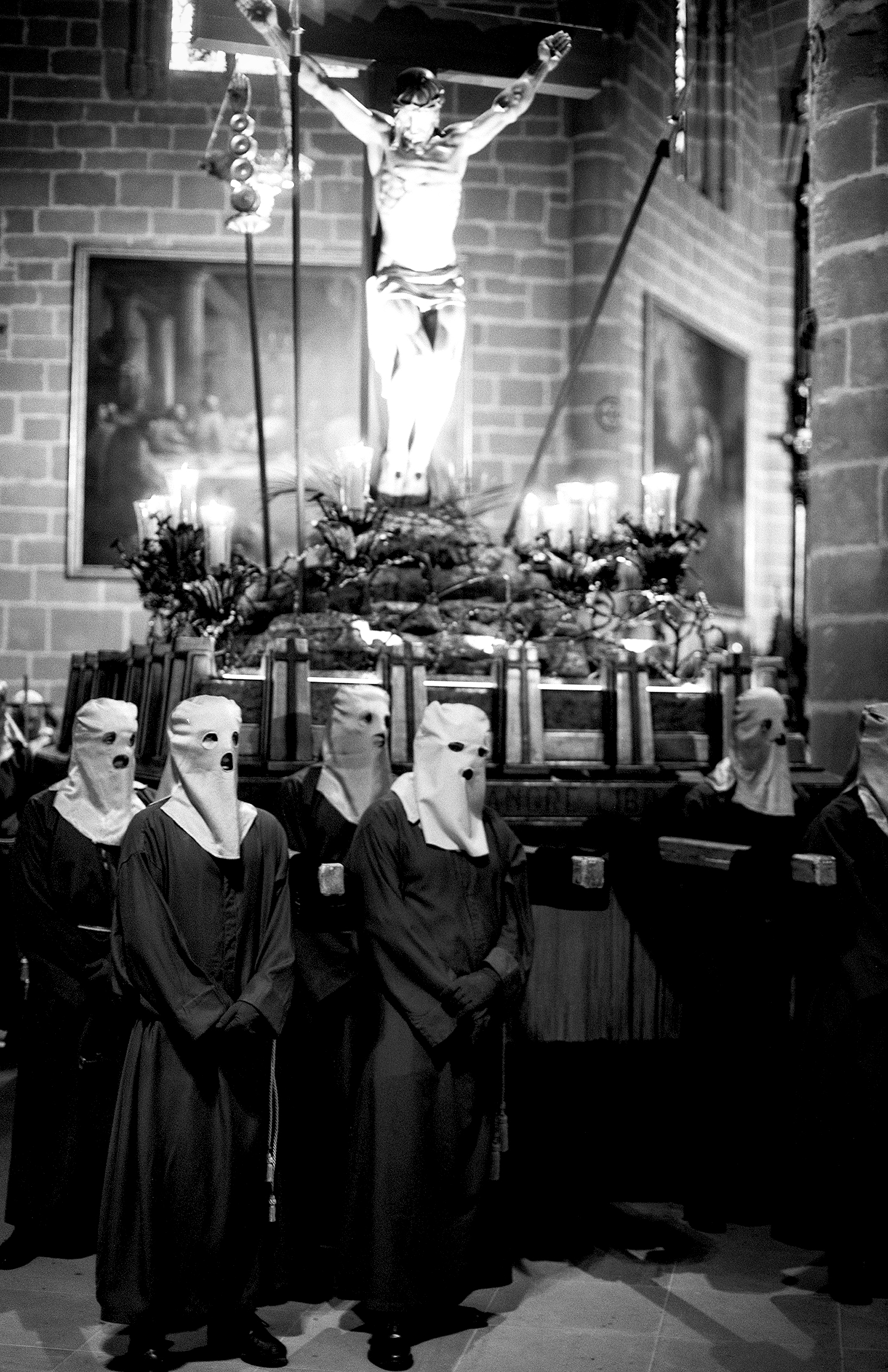 Religious procession with crucifix and hooded figures in traditional ceremony costume