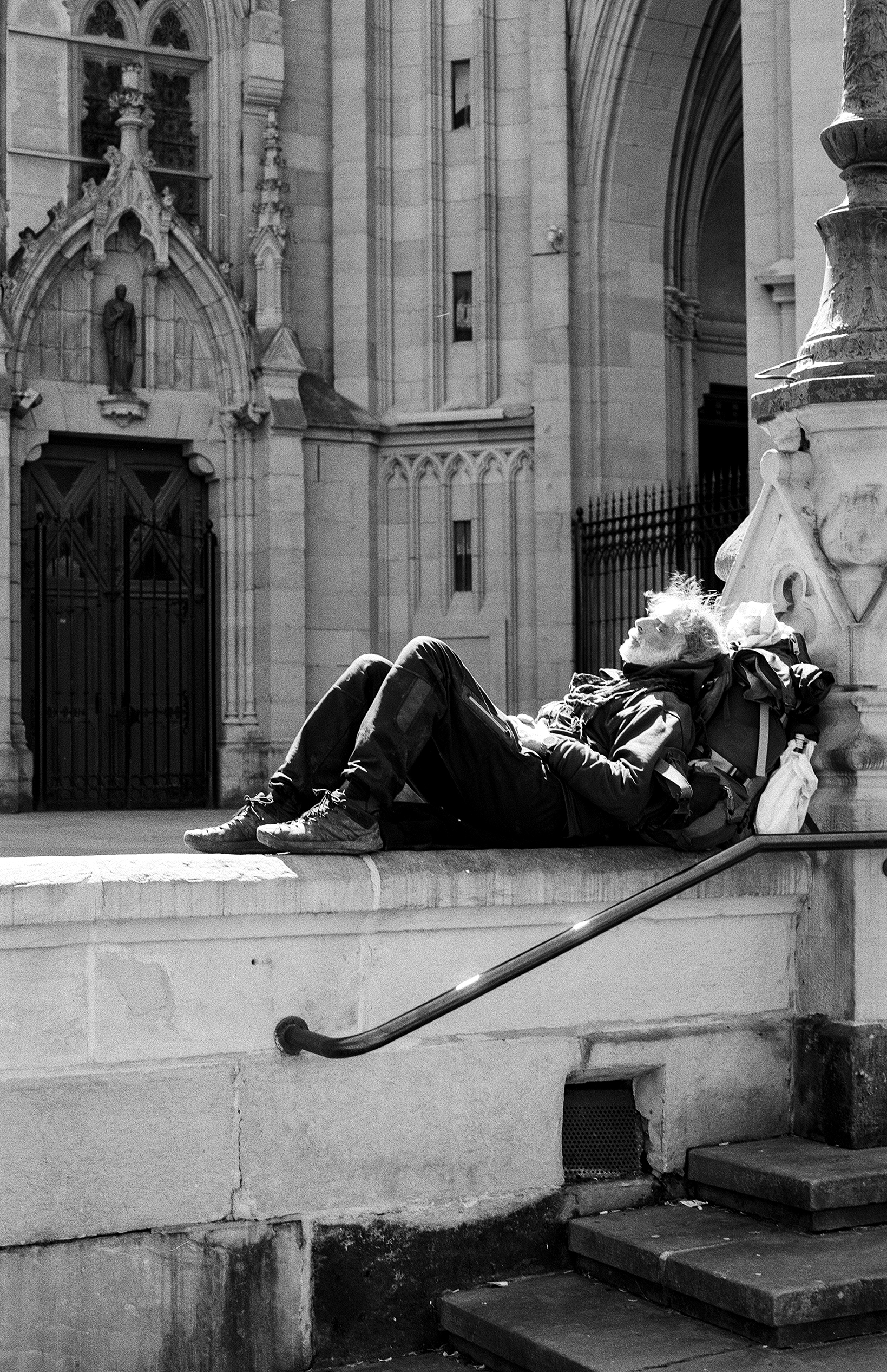 Person lying on stone steps beside Gothic cathedral with architectural details