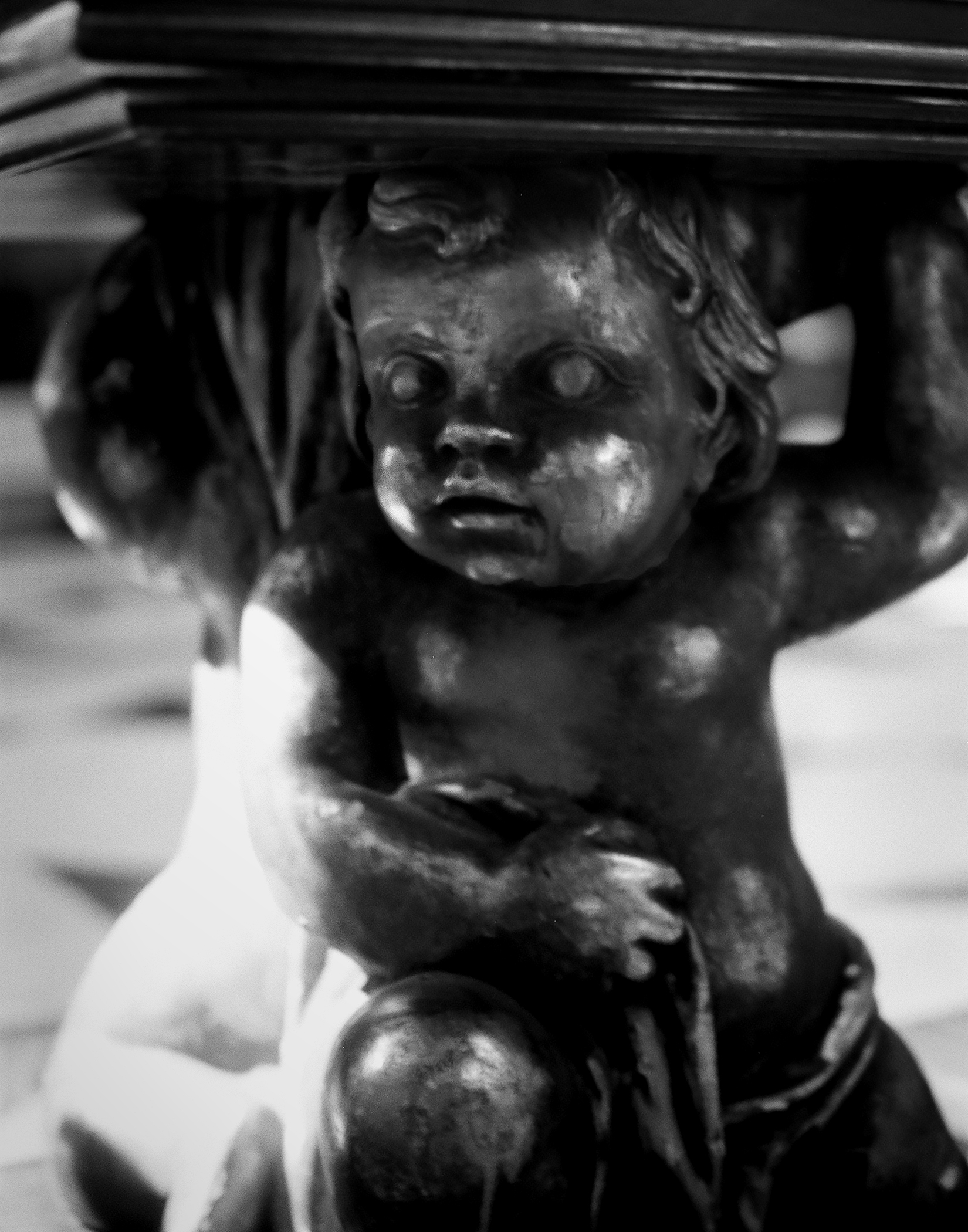 Stone cherub or cupid sculpture detail with weathered patina and focused gaze