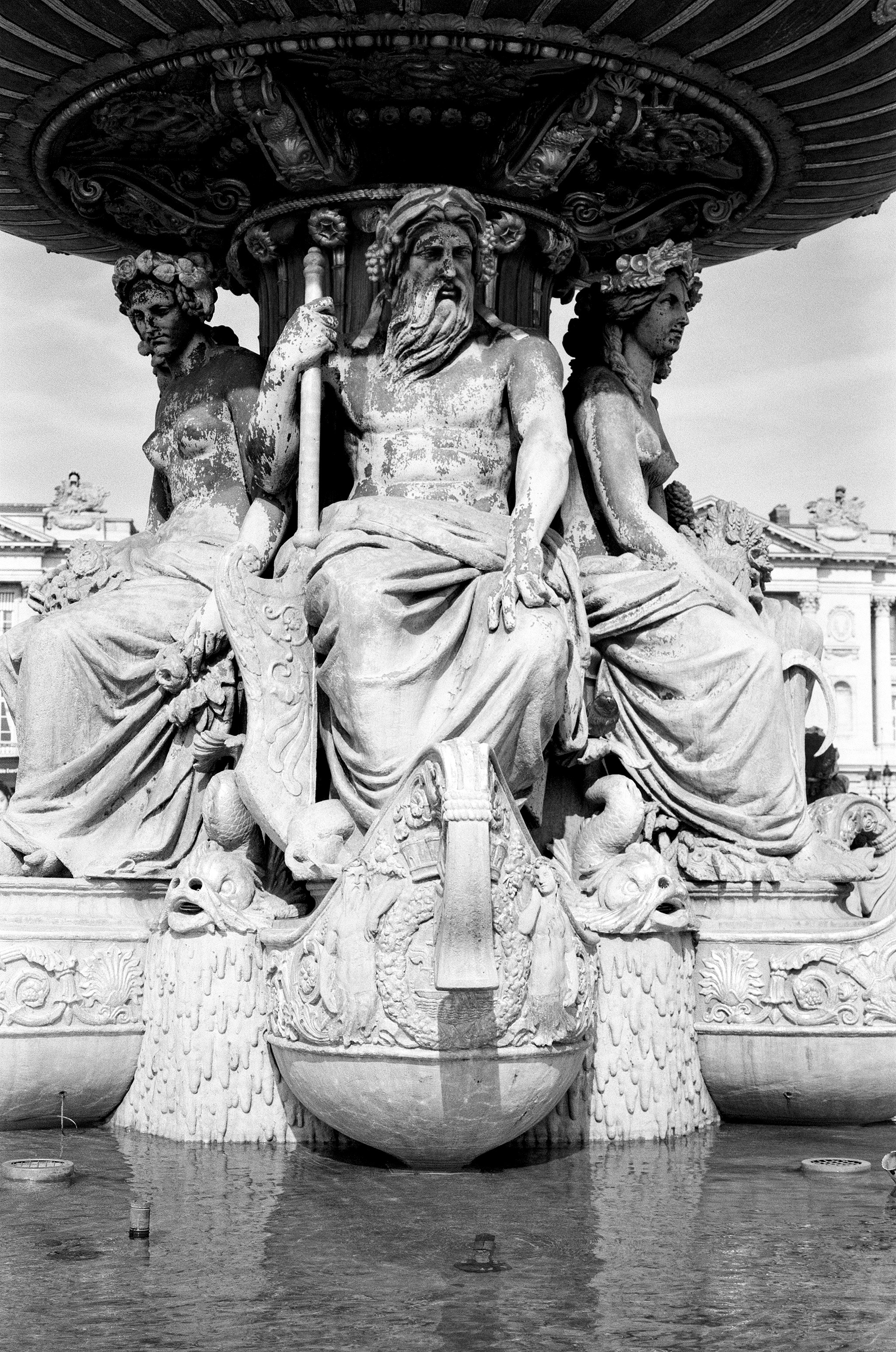 Louvre museum facade with Jules Ferry monument in foreground and lone figure seated at base
