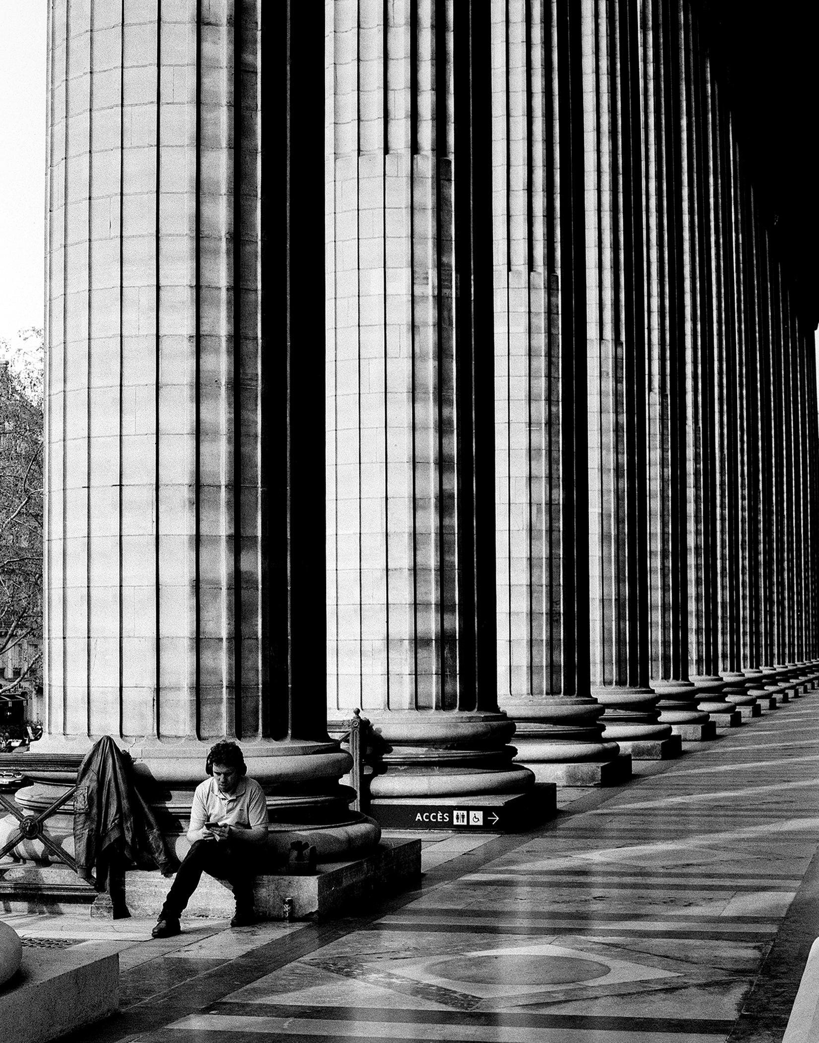 Person resting against large modernist column with grid pattern in symmetrical architectural space