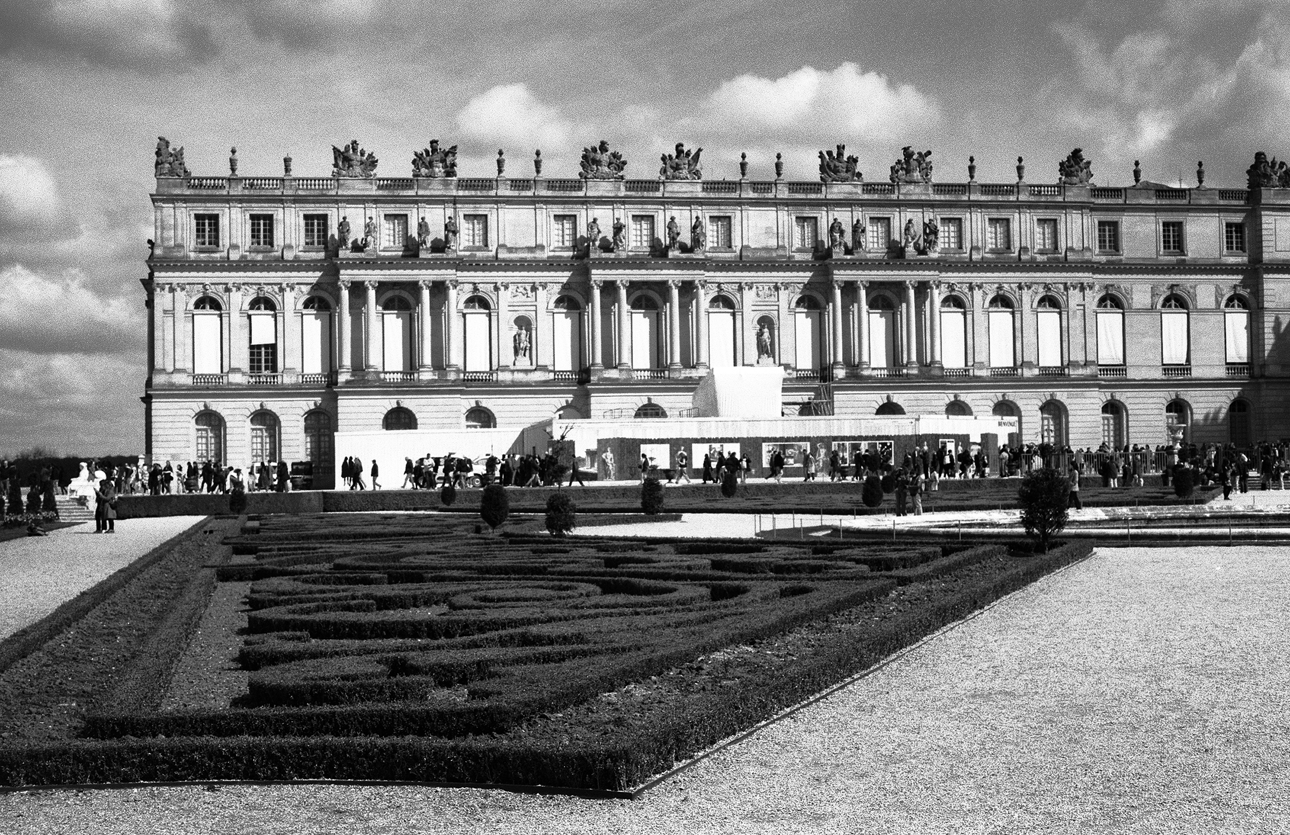 Versailles palace exterior with white classical portico and manicured formal gardens