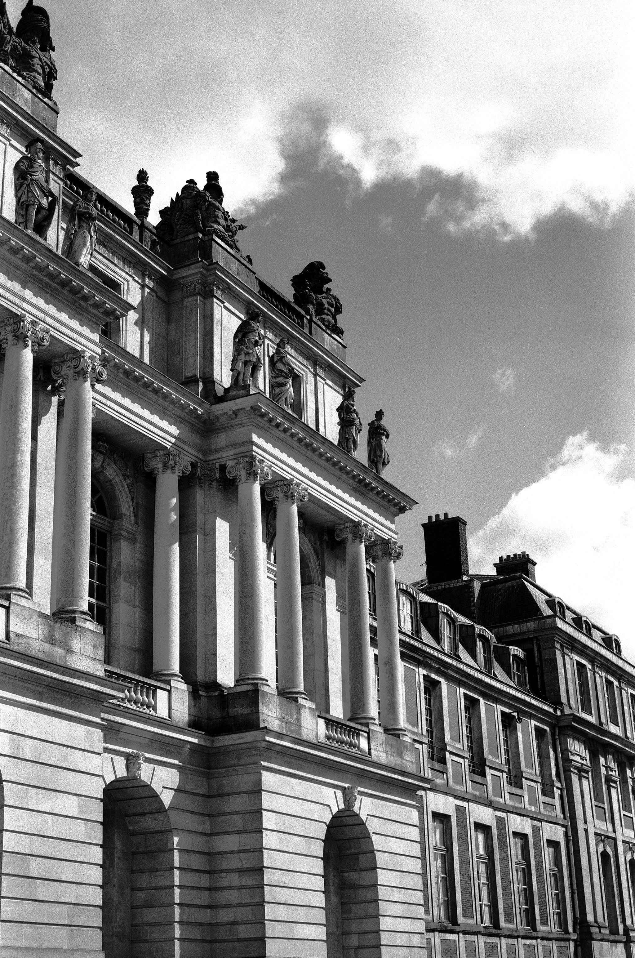 Classical building facade with tall fluted columns and sculptural relief figures at top