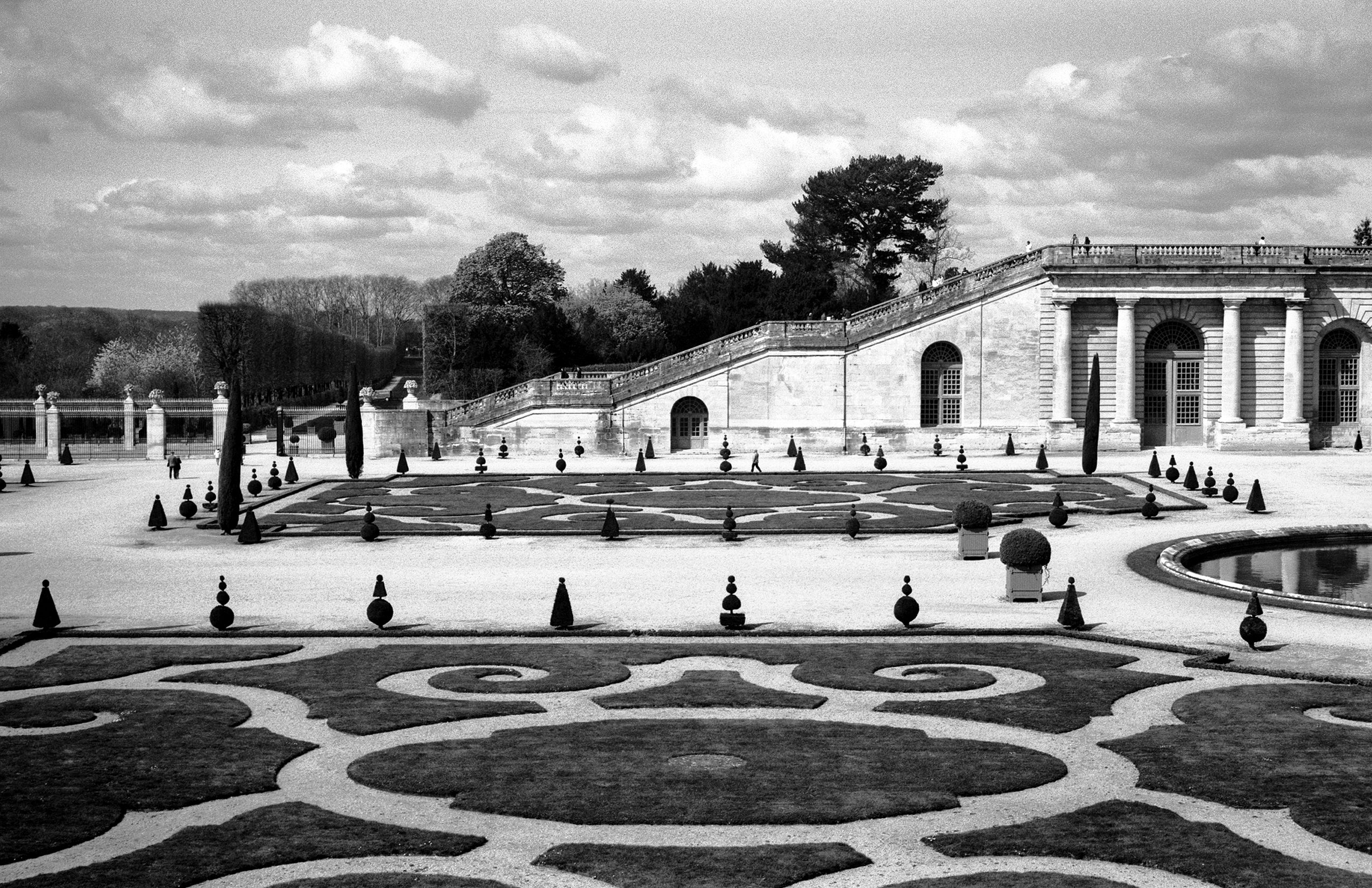 Versailles palace garden with geometric white and dark patterns, topiary and arched pavilion
