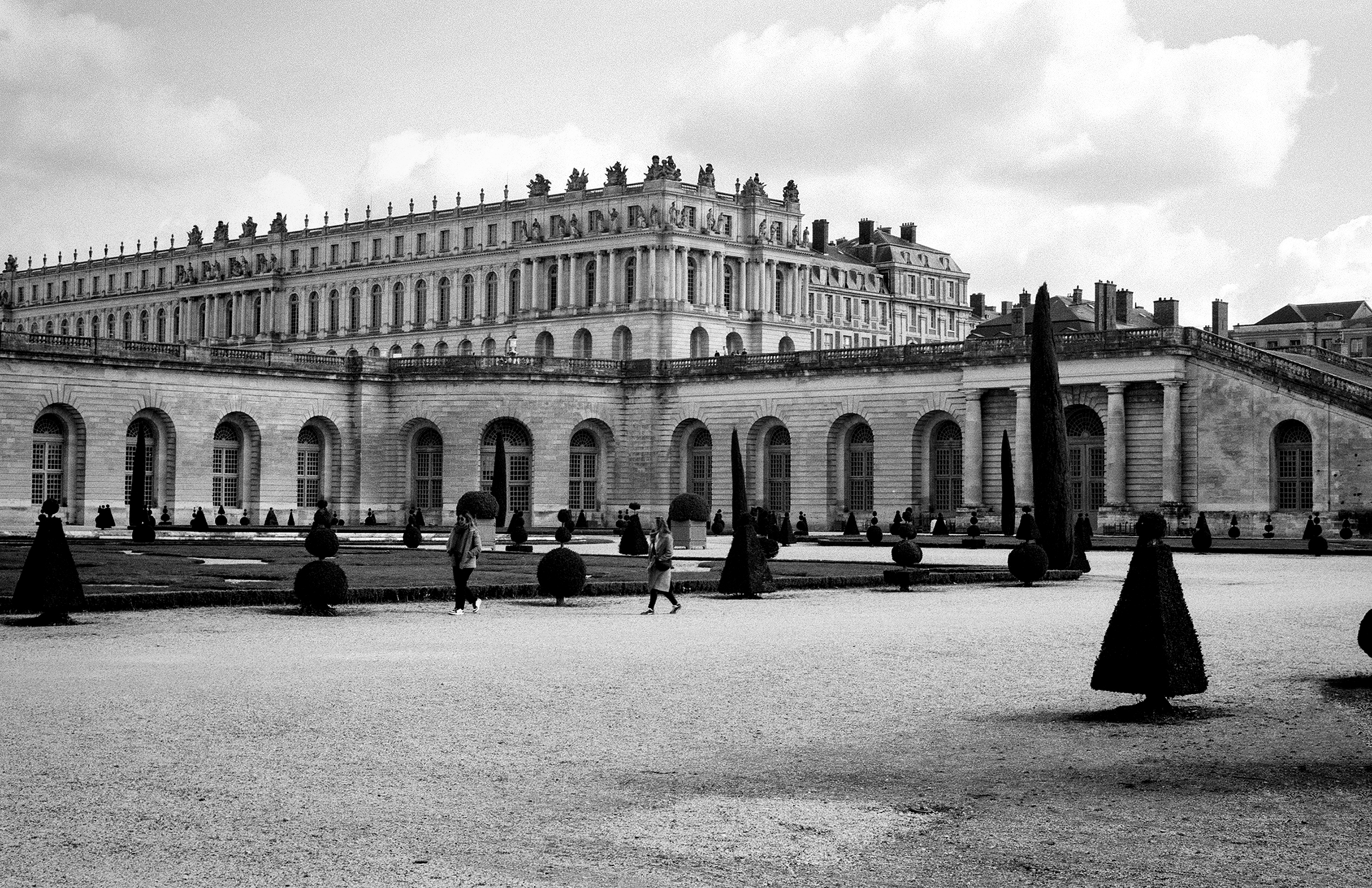 Versailles palace with manicured gardens, cypress trees and topiary arrangements
