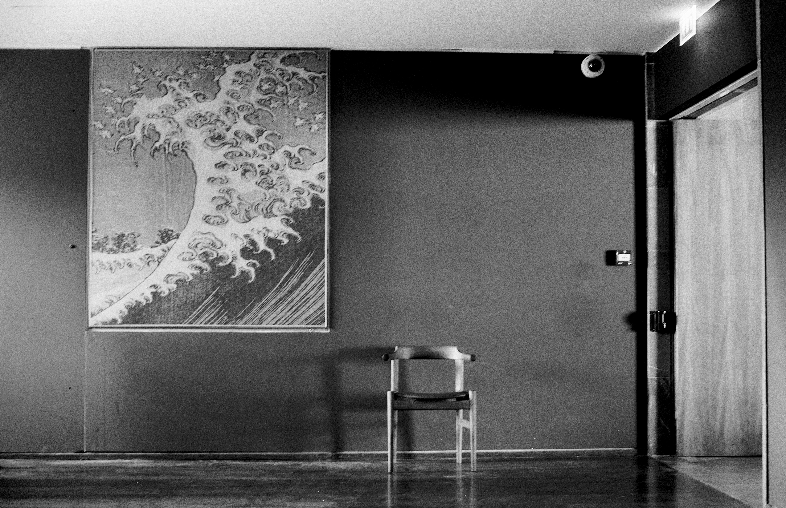 Museum interior with classical wave print artwork on wall and wooden chair on dark floor