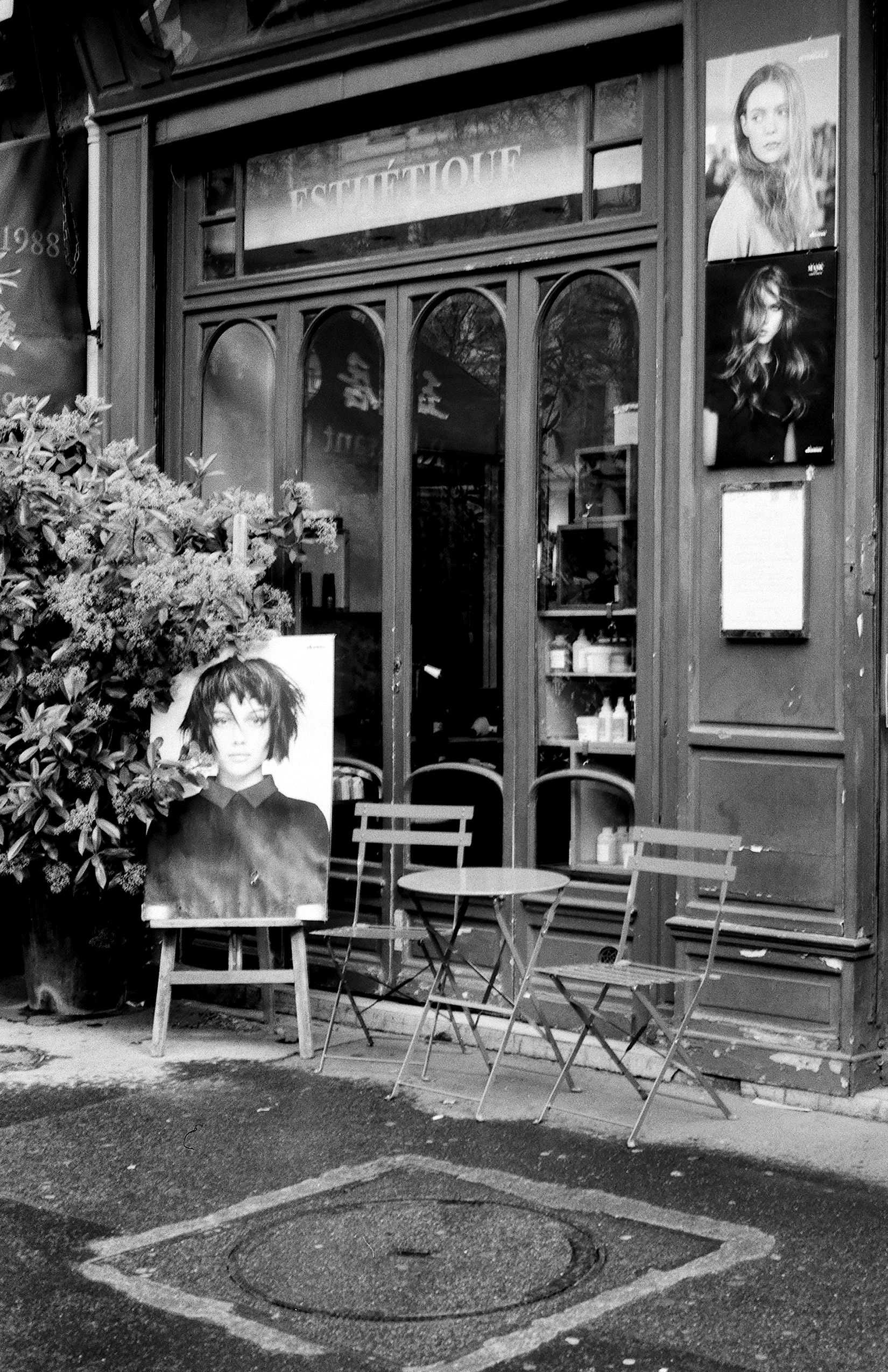 Boutique shop with fashion mannequins in window on Paris street with cafe seating