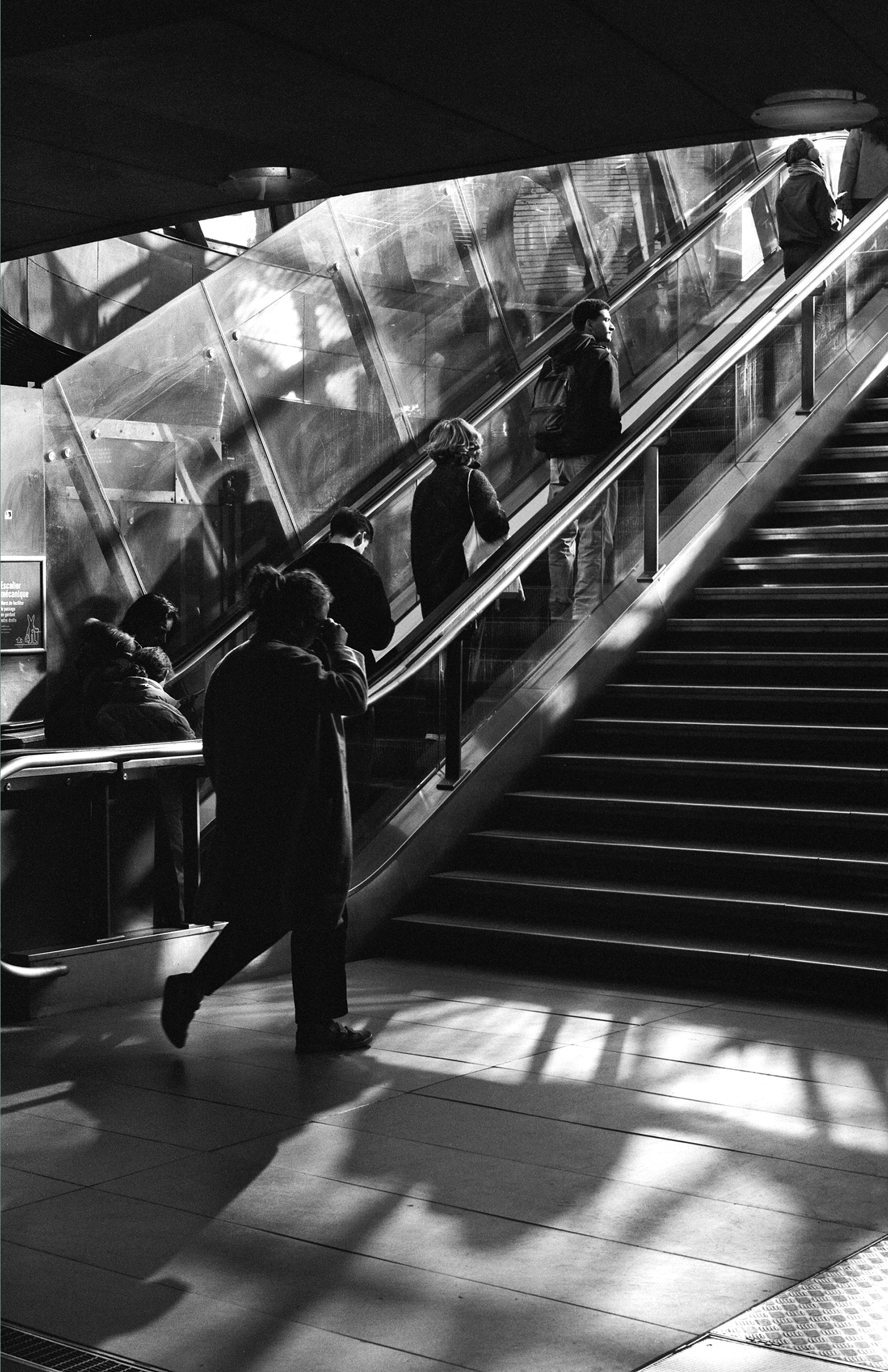 Metro escalator interior with glass enclosure and passengers ascending