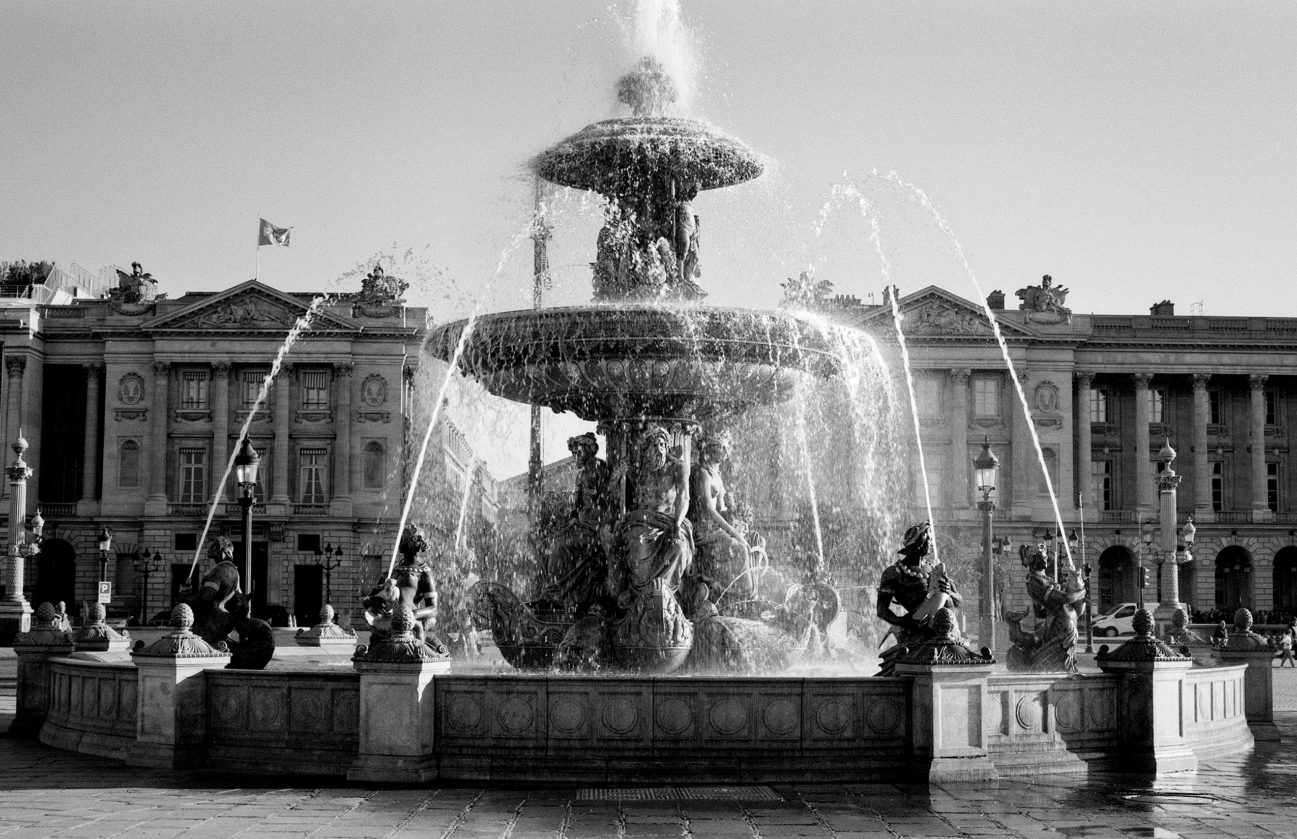 Place de la Concorde fountain with sculptural figures and classical Haussmann buildings under overcast sky