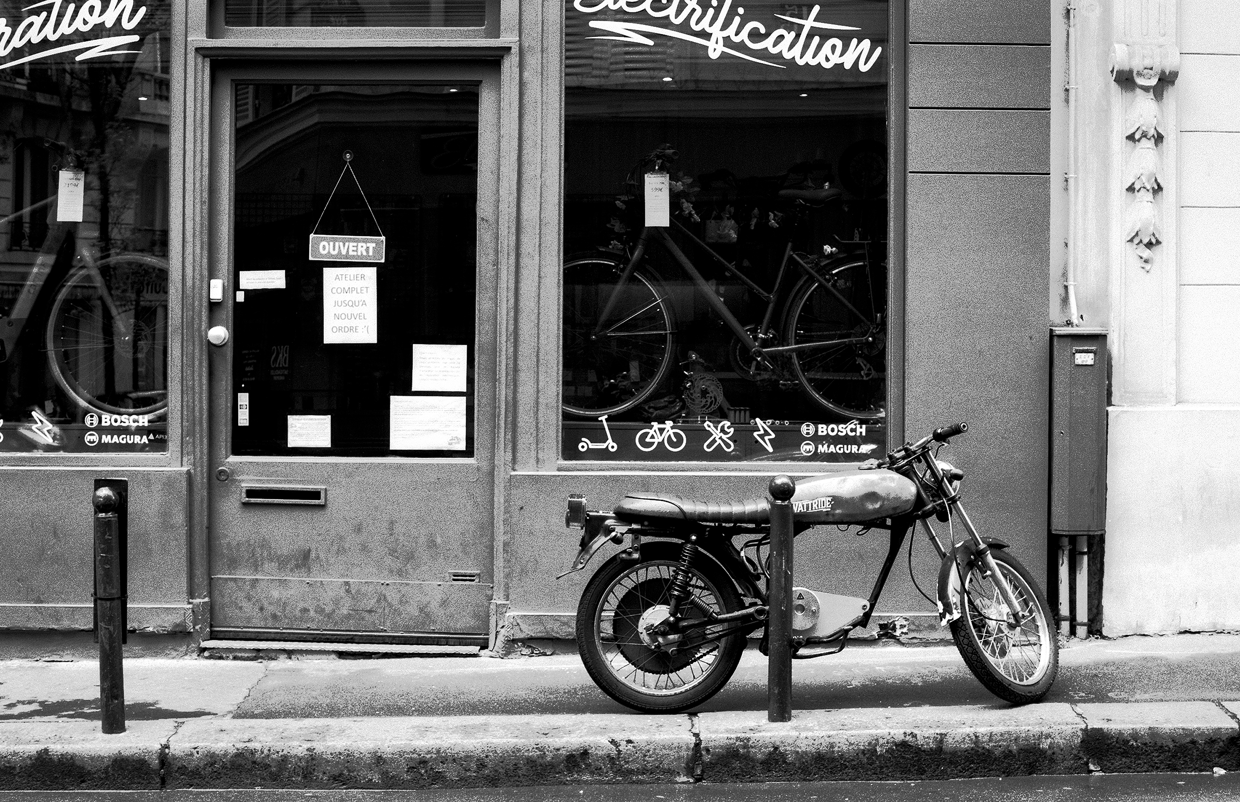 Open Paris bicycle shop with Bosch and Magura signs and parked moped on street