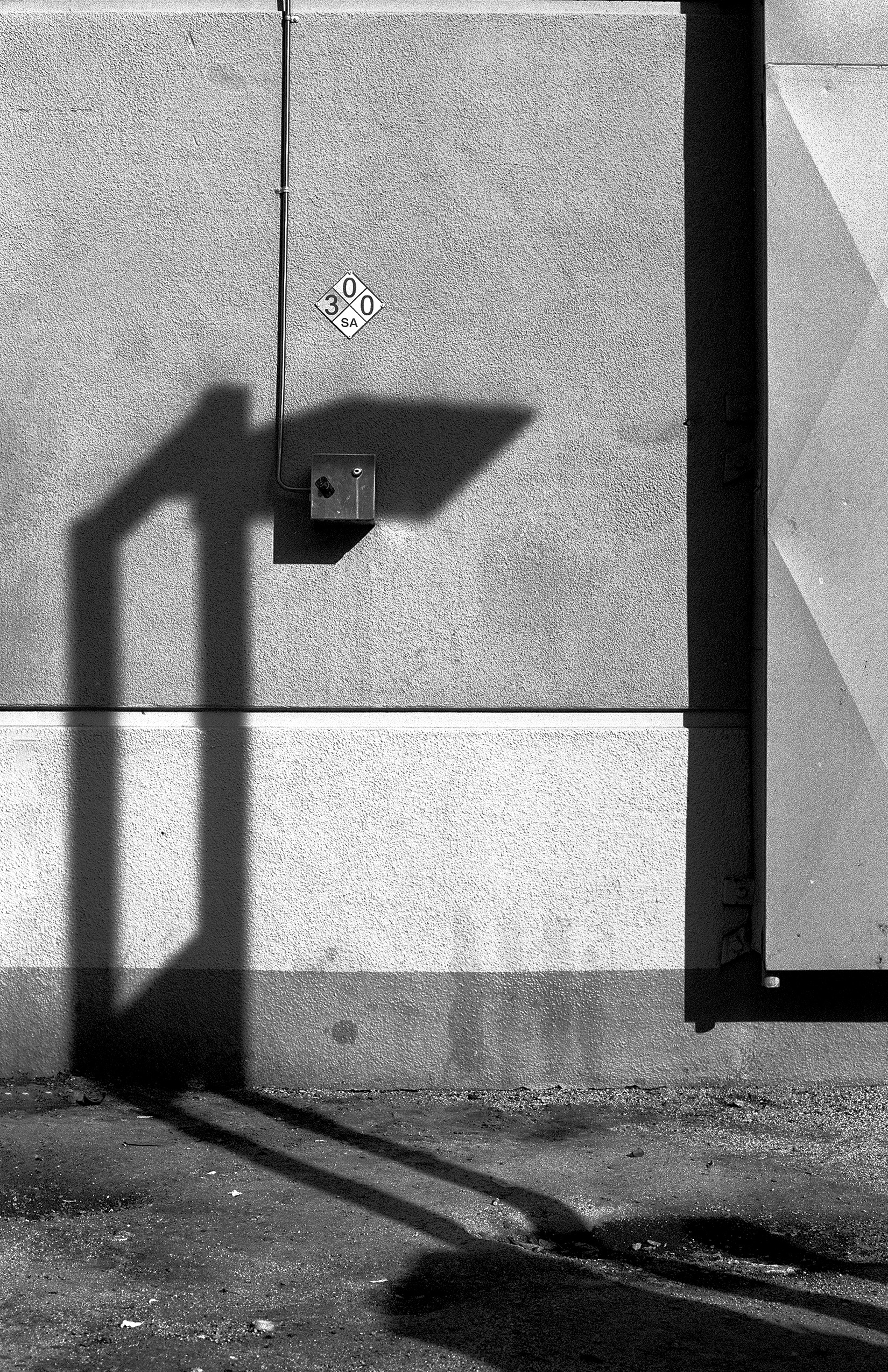 Minimalist wall composition with street sign shadow NFPA hazard diamond electrical box geometric shadows and lines