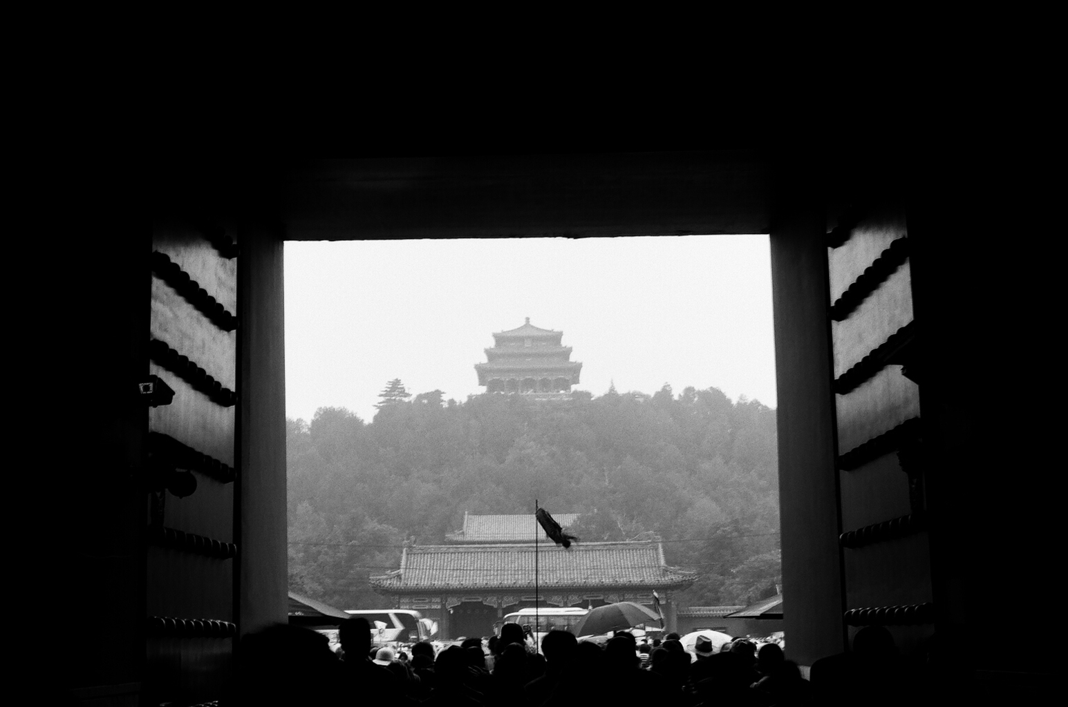 View through Forbidden City gate to distant pagoda on forested hill