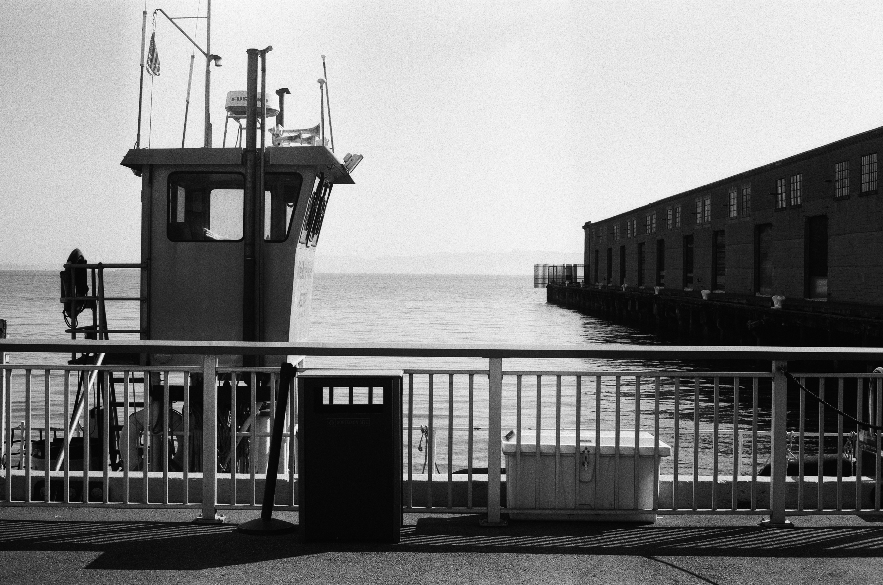 Ferry vessel with cabin at dock alongside industrial waterfront warehouse buildings