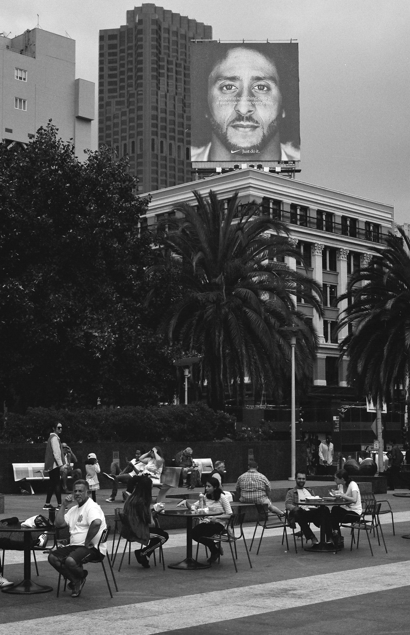 Civic Center plaza scene with Nike Kaepernick billboard and crowds with palm trees