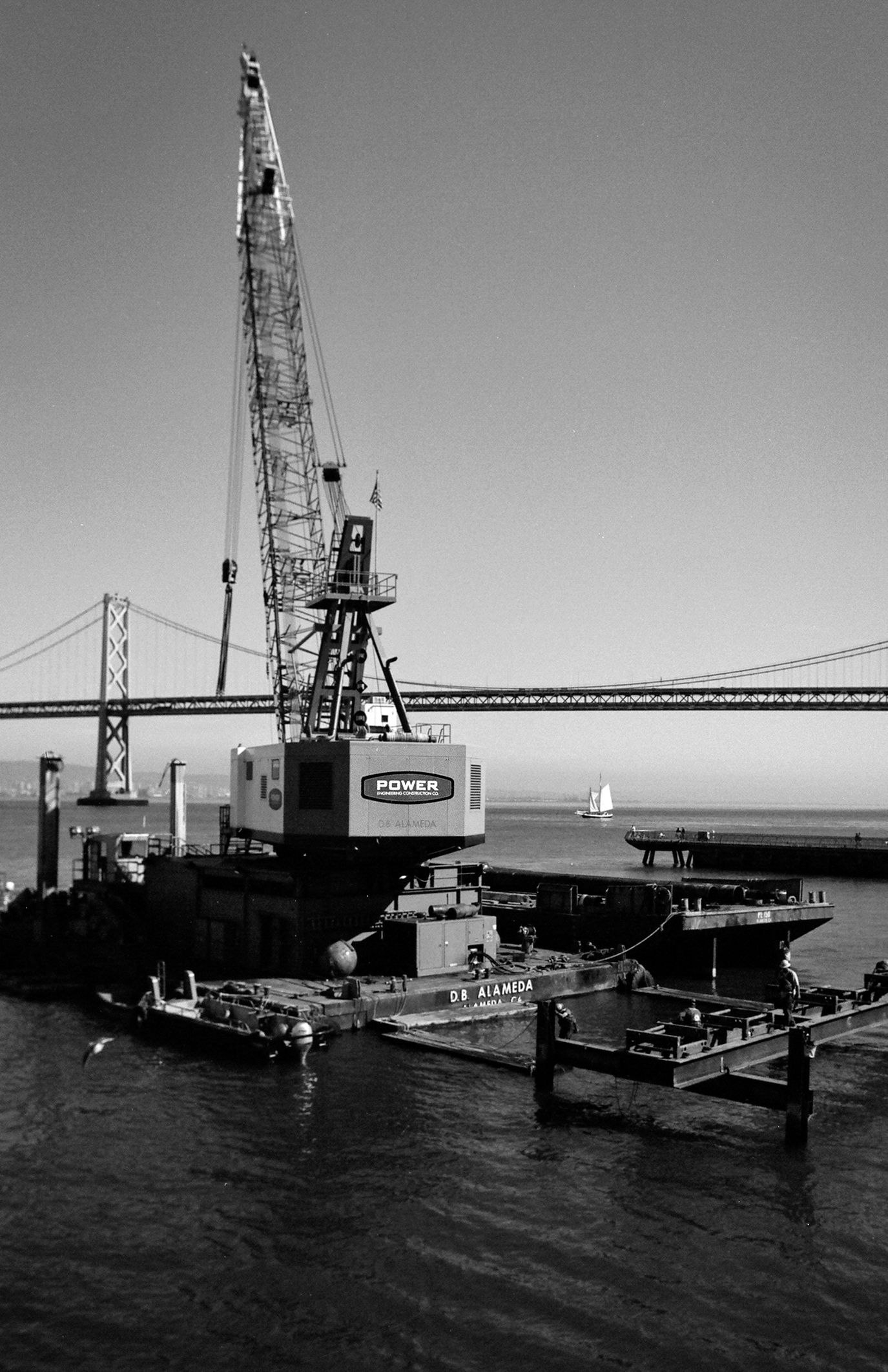 Industrial cargo crane with tall boom at waterfront dock with Golden Gate Bridge
