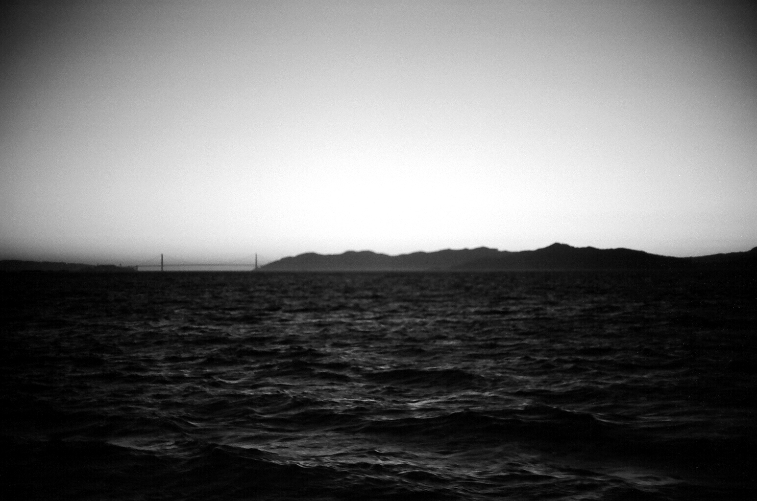 Water view with Golden Gate Bridge towers visible in distance under overcast sky