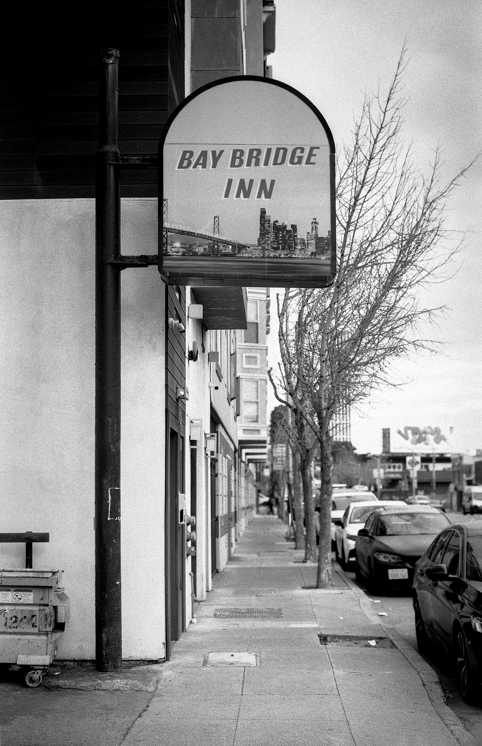 Bay Bridge Inn vintage hotel sign with bridge illustration on quiet street with bare trees and parked cars
