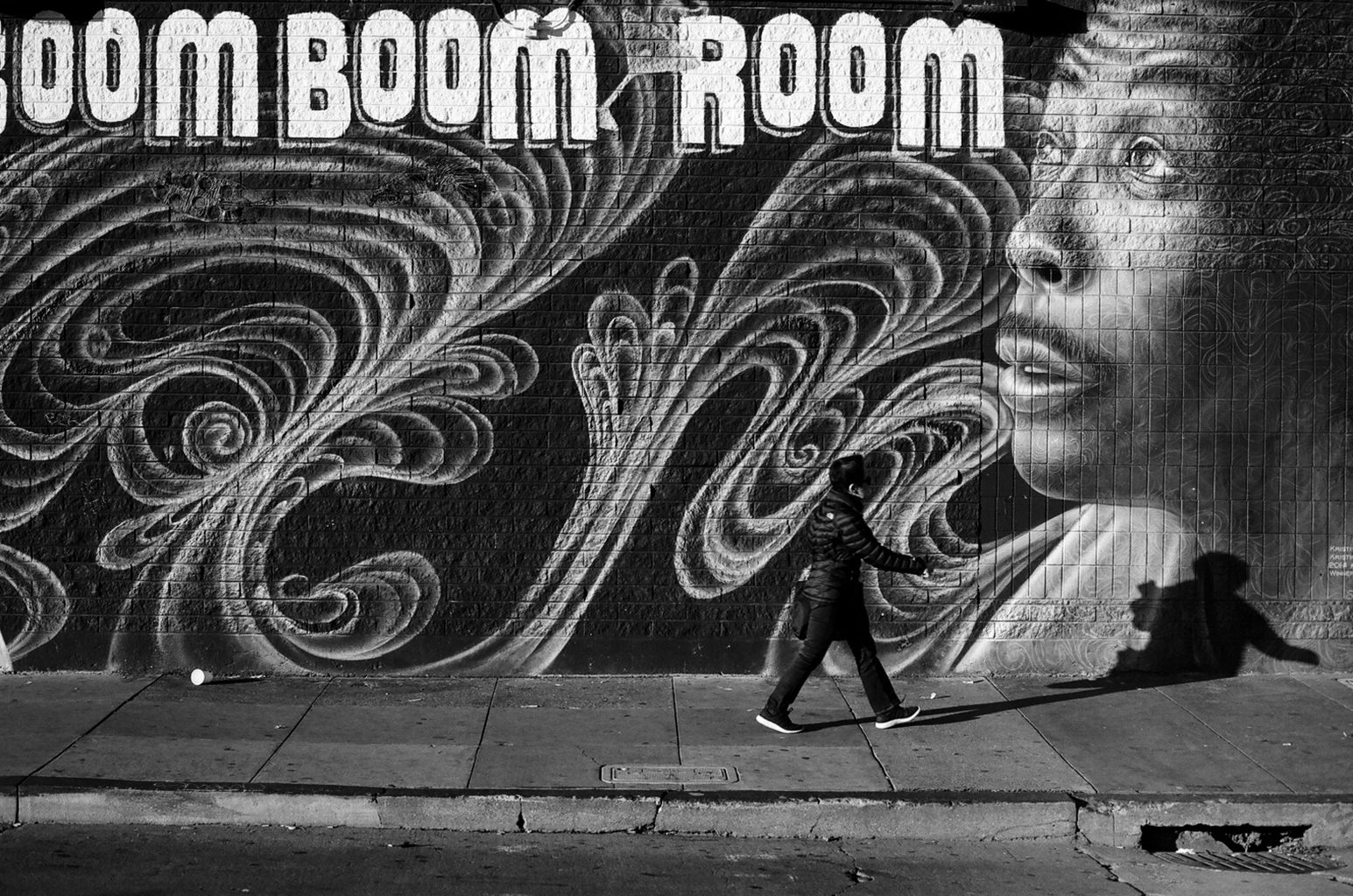 Person walking past large decorative mural with ornate spiral patterns on building
