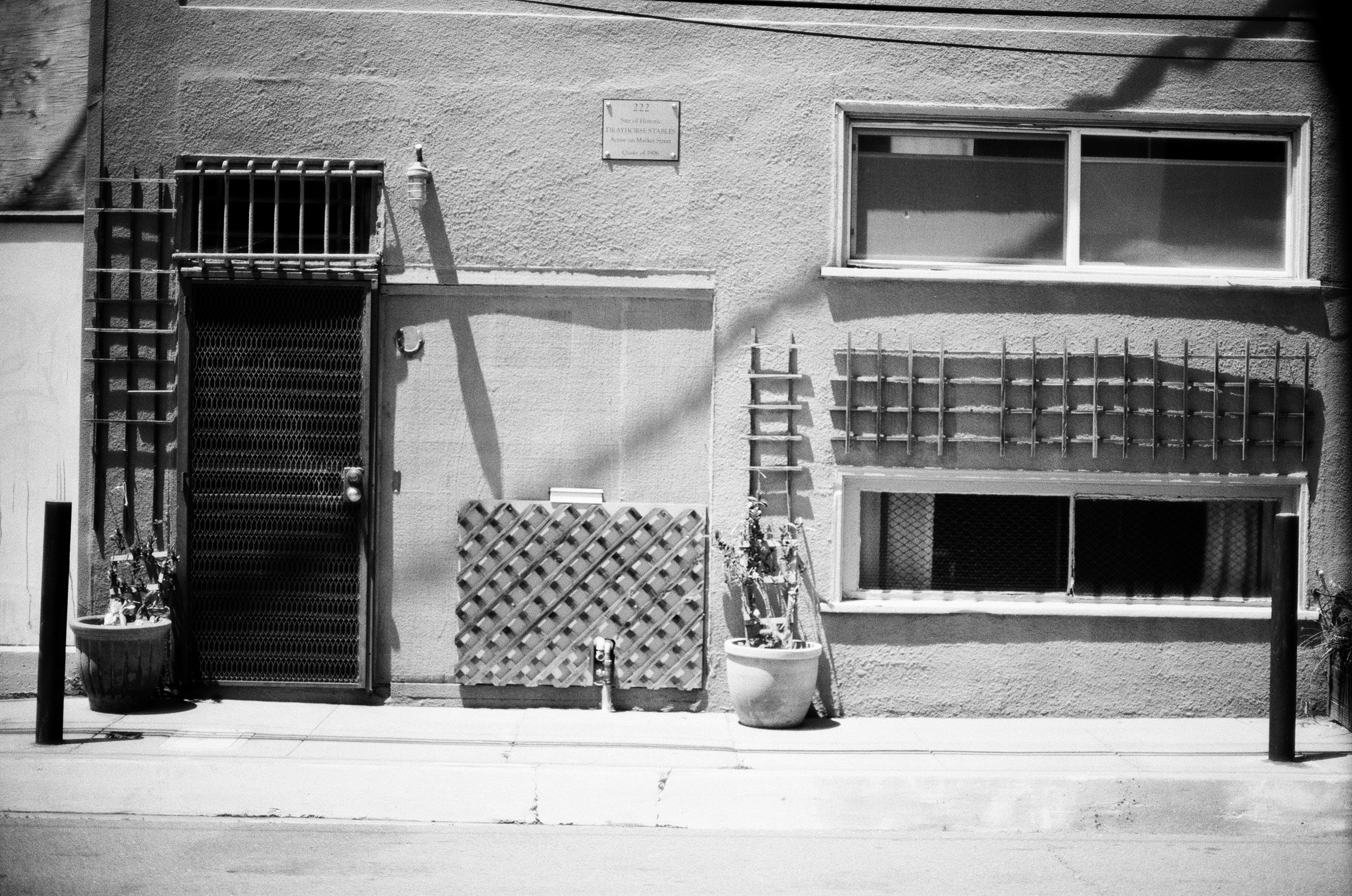 Residential facade with metal security gate mesh door and small windows on concrete wall