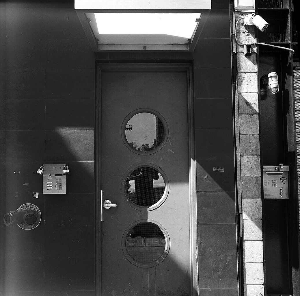 Overhead view of dryer vent circles and padlocked mailbox on institutional door with geometric composition