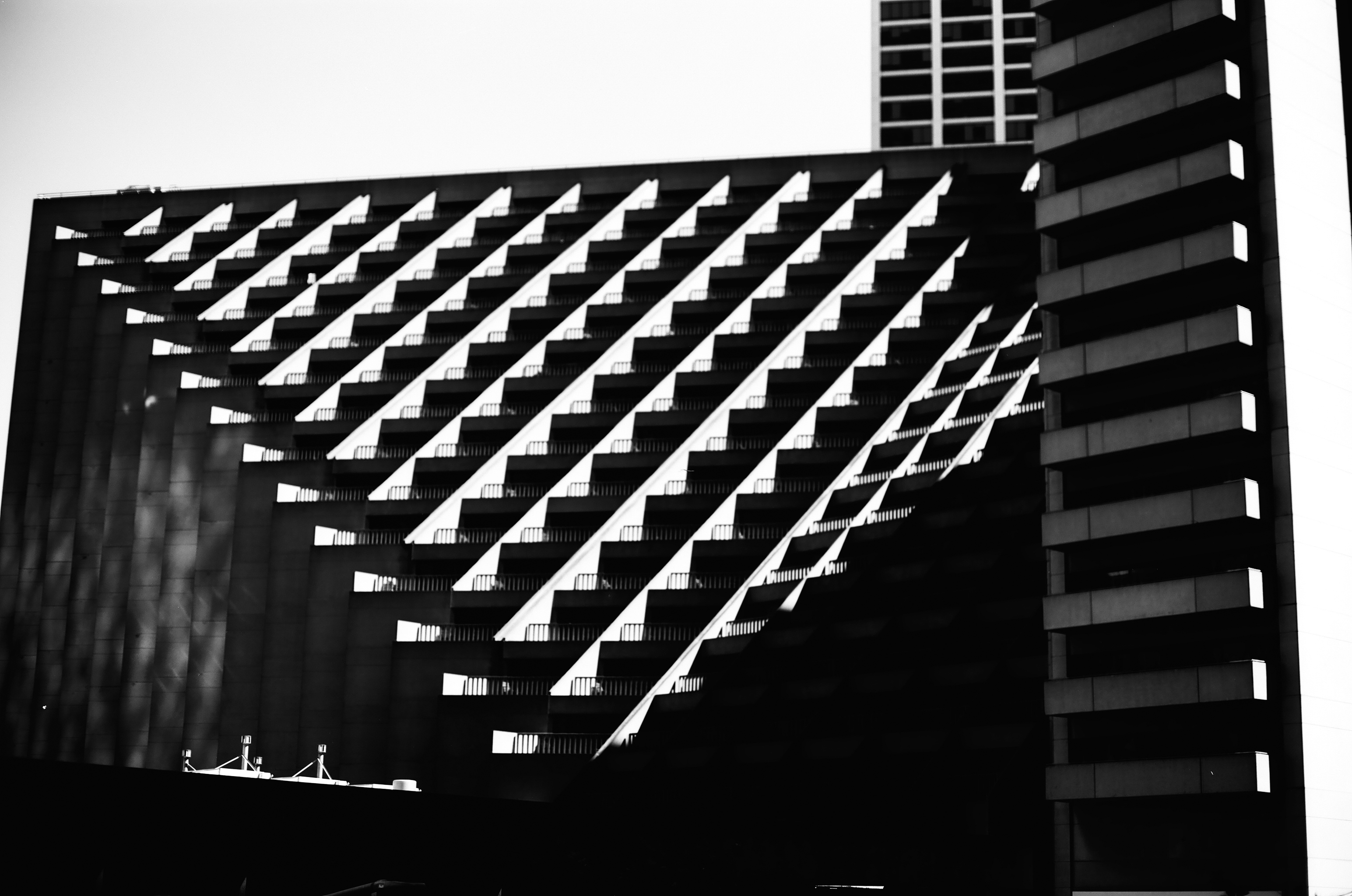 Modern building facade with geometric diamond pattern in black and white creating shadows